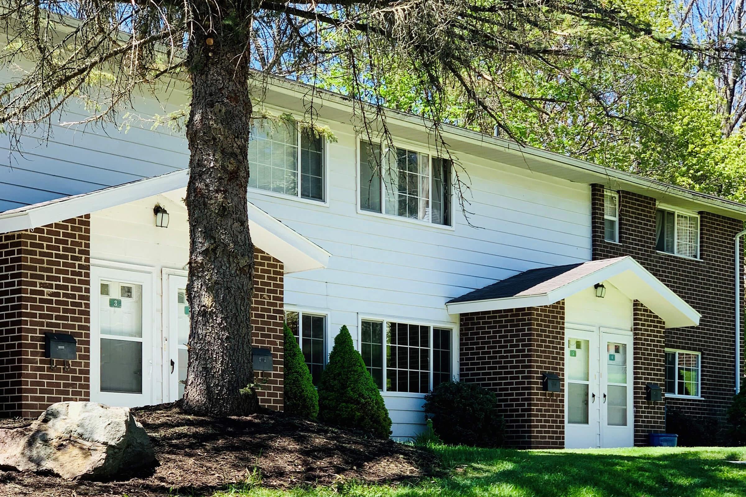 a house with bushes in front of a brick building