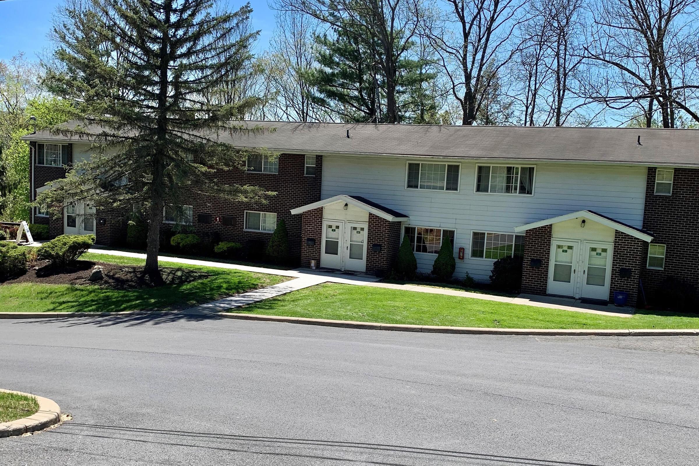 a large brick building with grass in front of a house