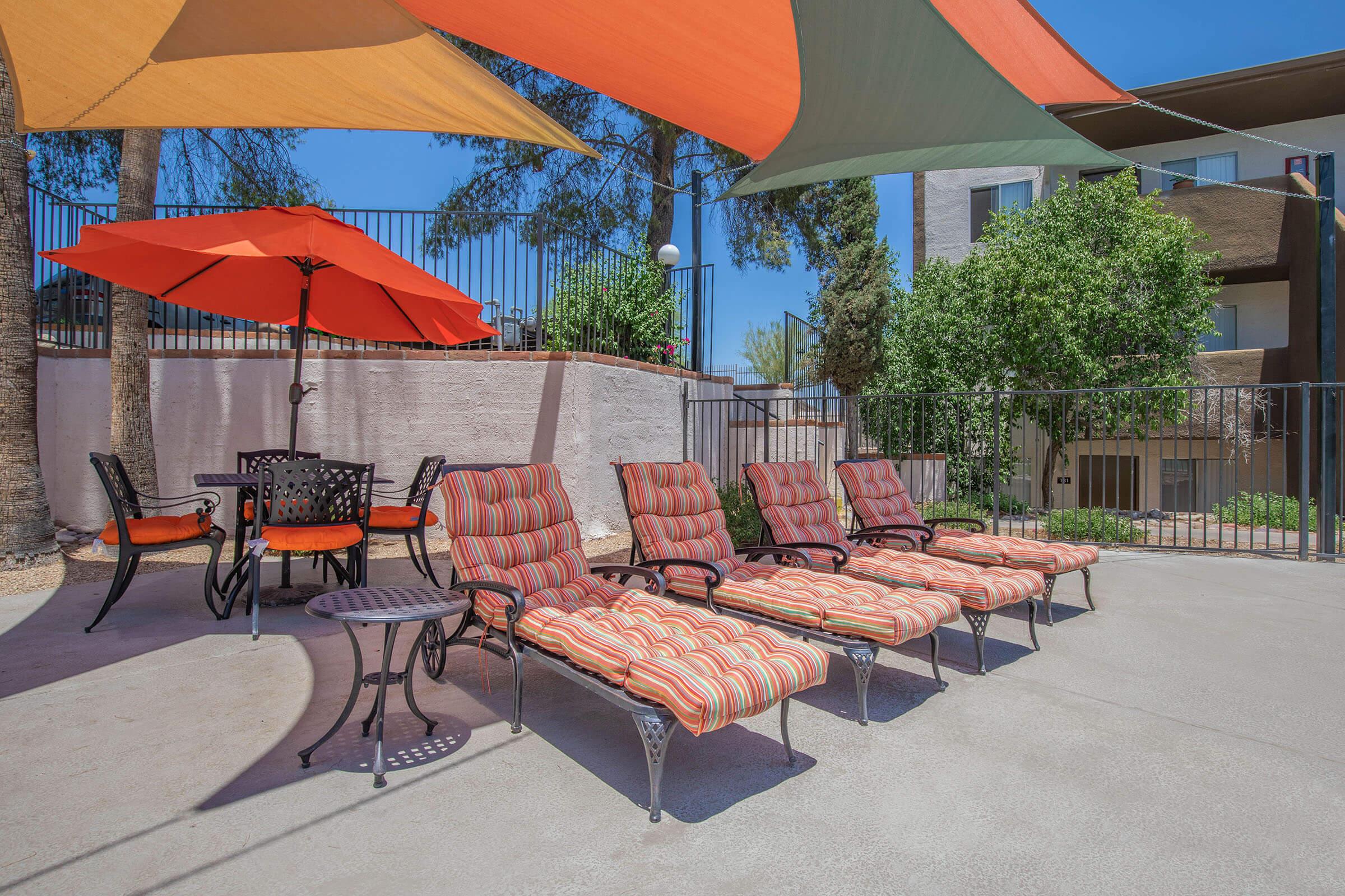 a group of lawn chairs sitting on top of an orange umbrella