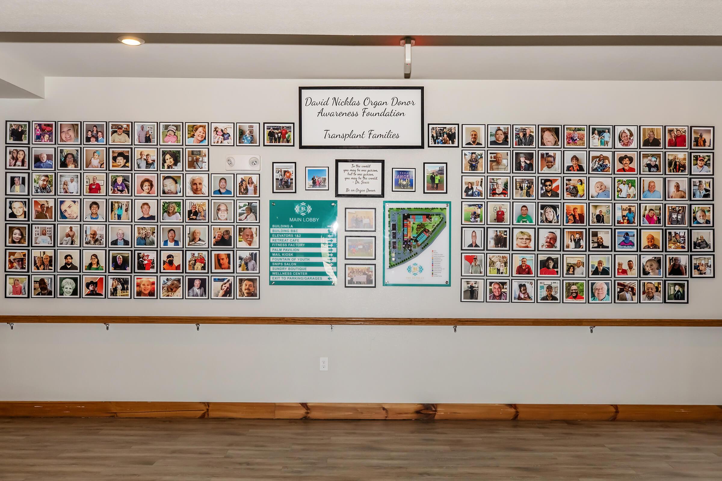 A wall displaying a collection of framed photos featuring individuals, accompanied by an informational plaque about the David Nicholas Organ Donors Awareness Foundation and its contributions to transplant awareness. The wall showcases various portraits organized in a grid format, highlighting the importance of organ donation.
