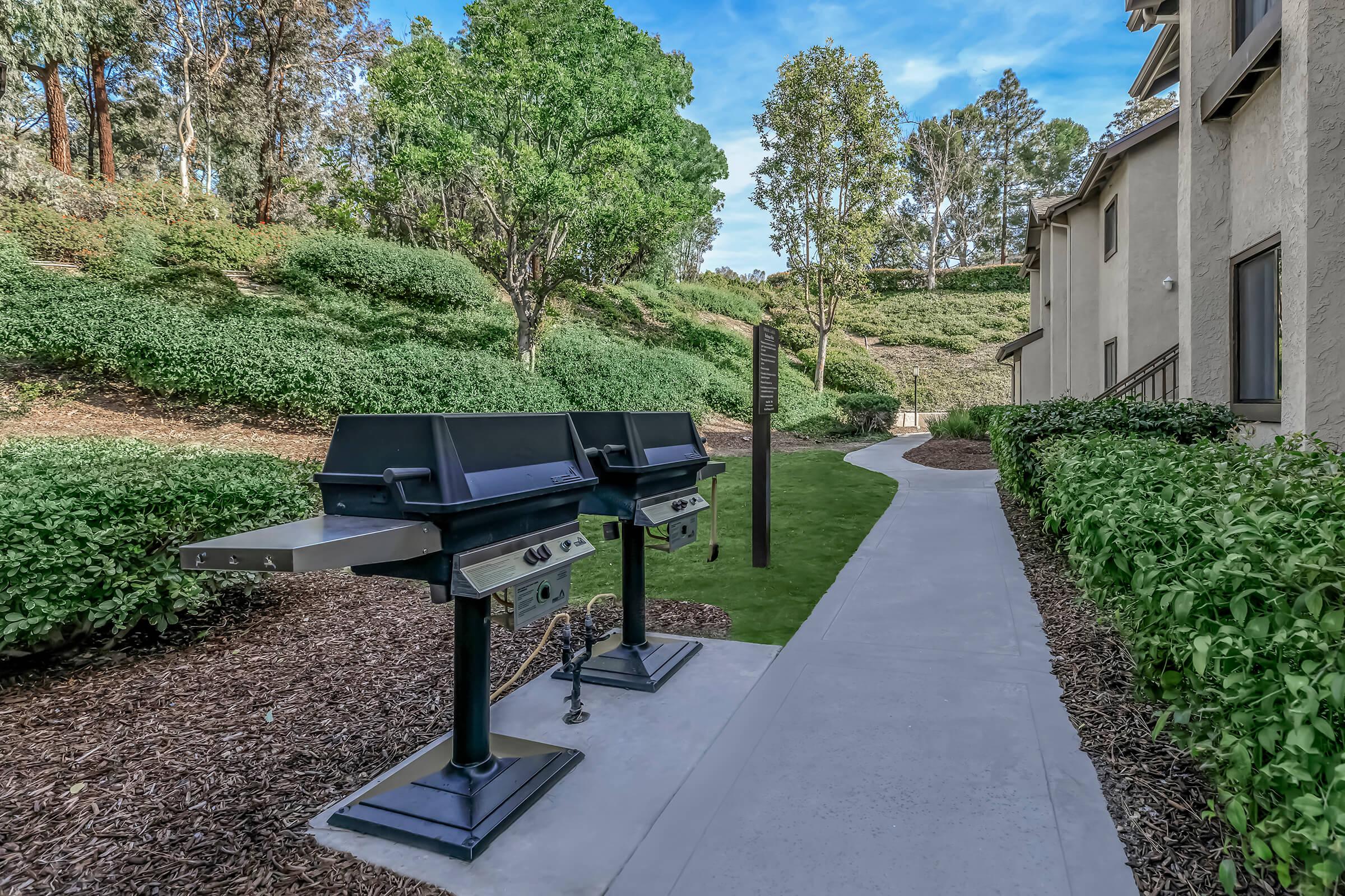 Two barbecues with green landscaping