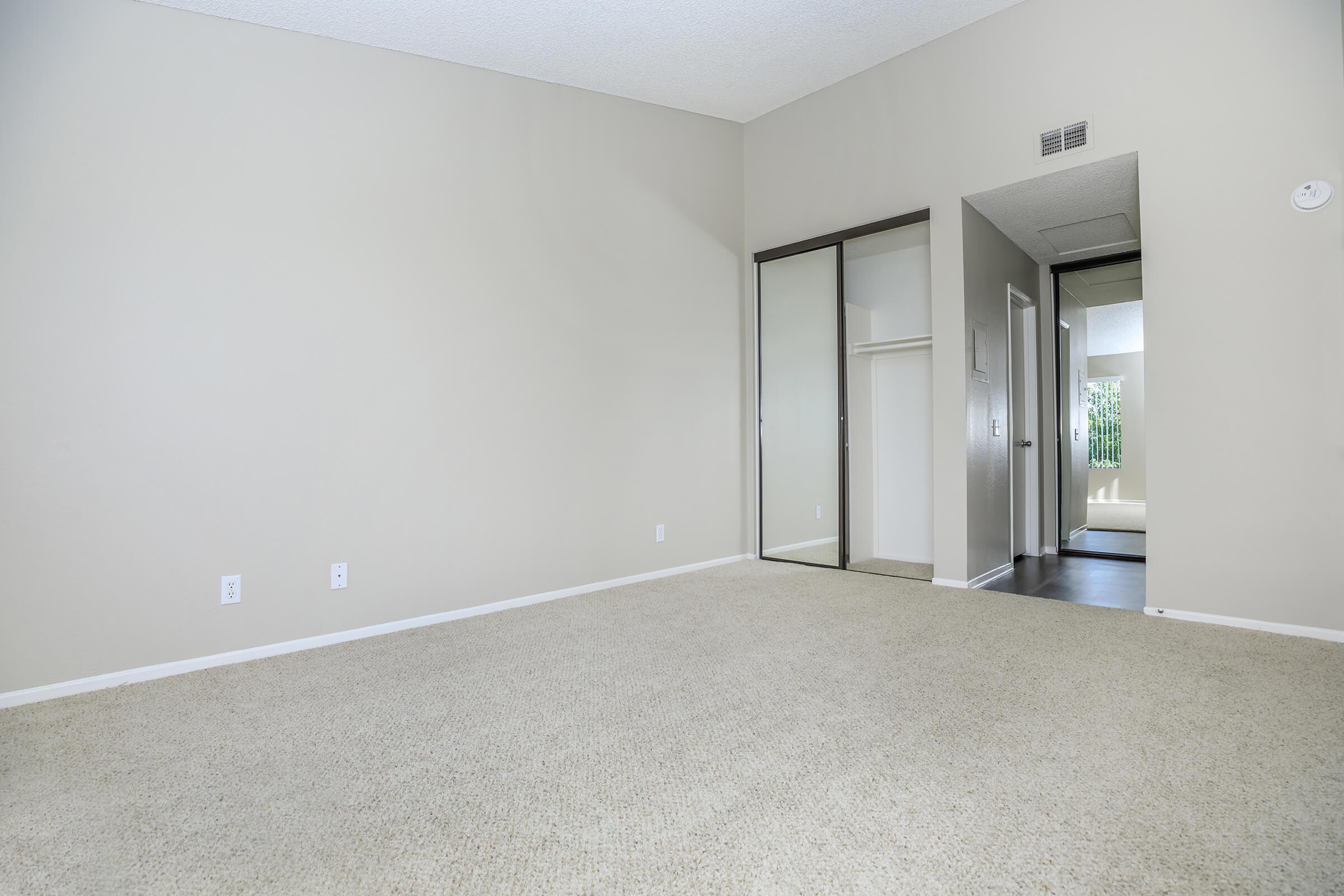 Carpeted bedroom with sliding mirror glass closet doors