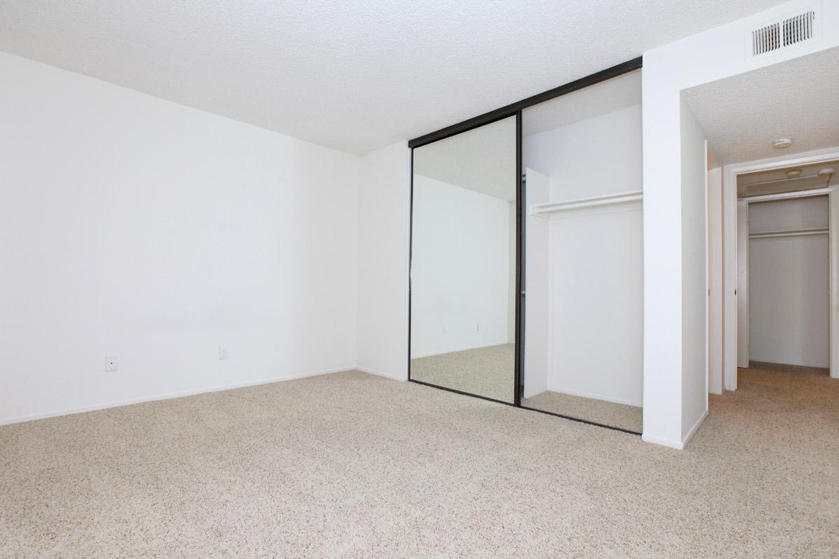 Unfurnished bedroom with open sliding mirror glass closet doors