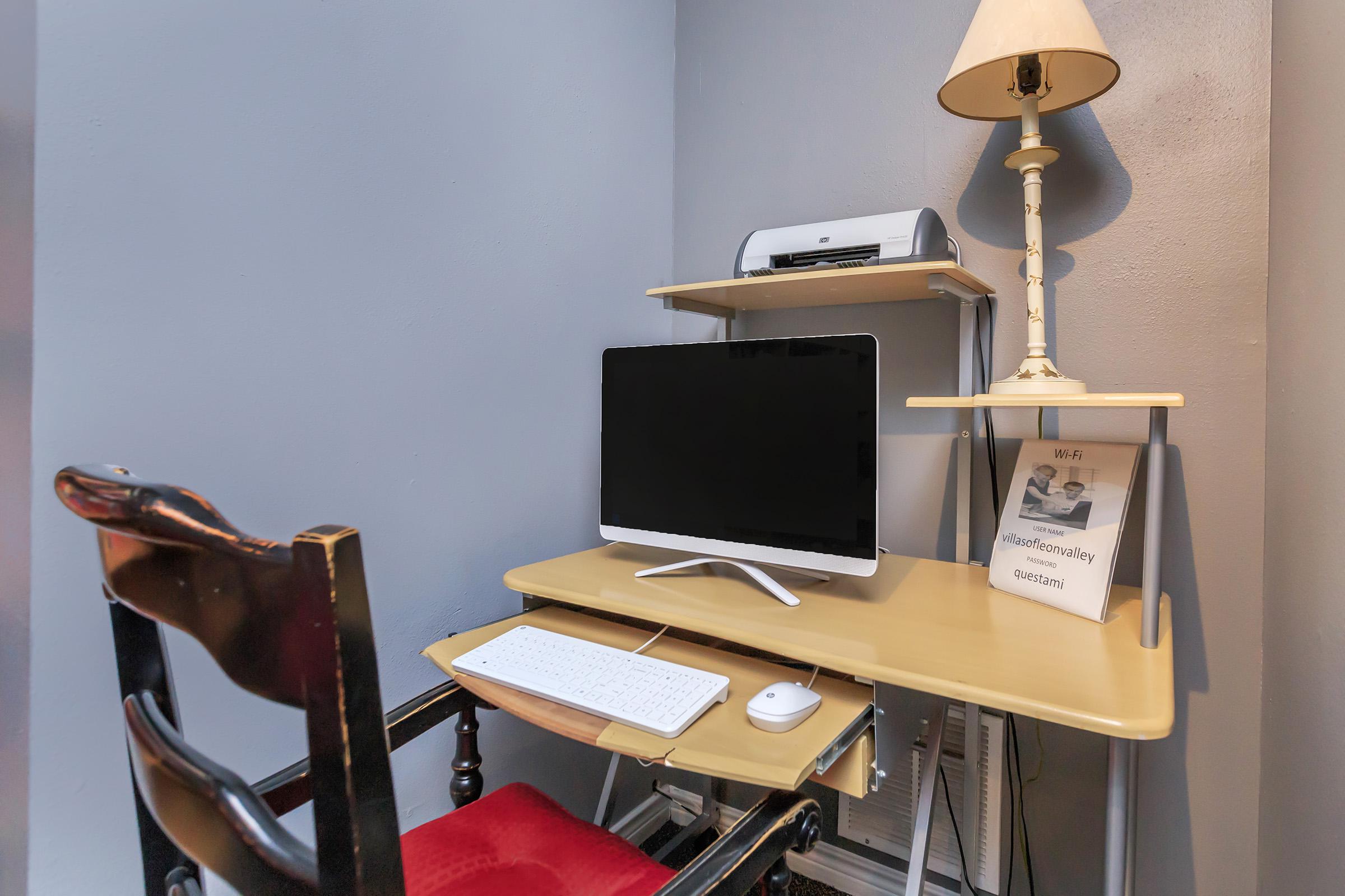 a desk with a laptop computer sitting on top of a chair