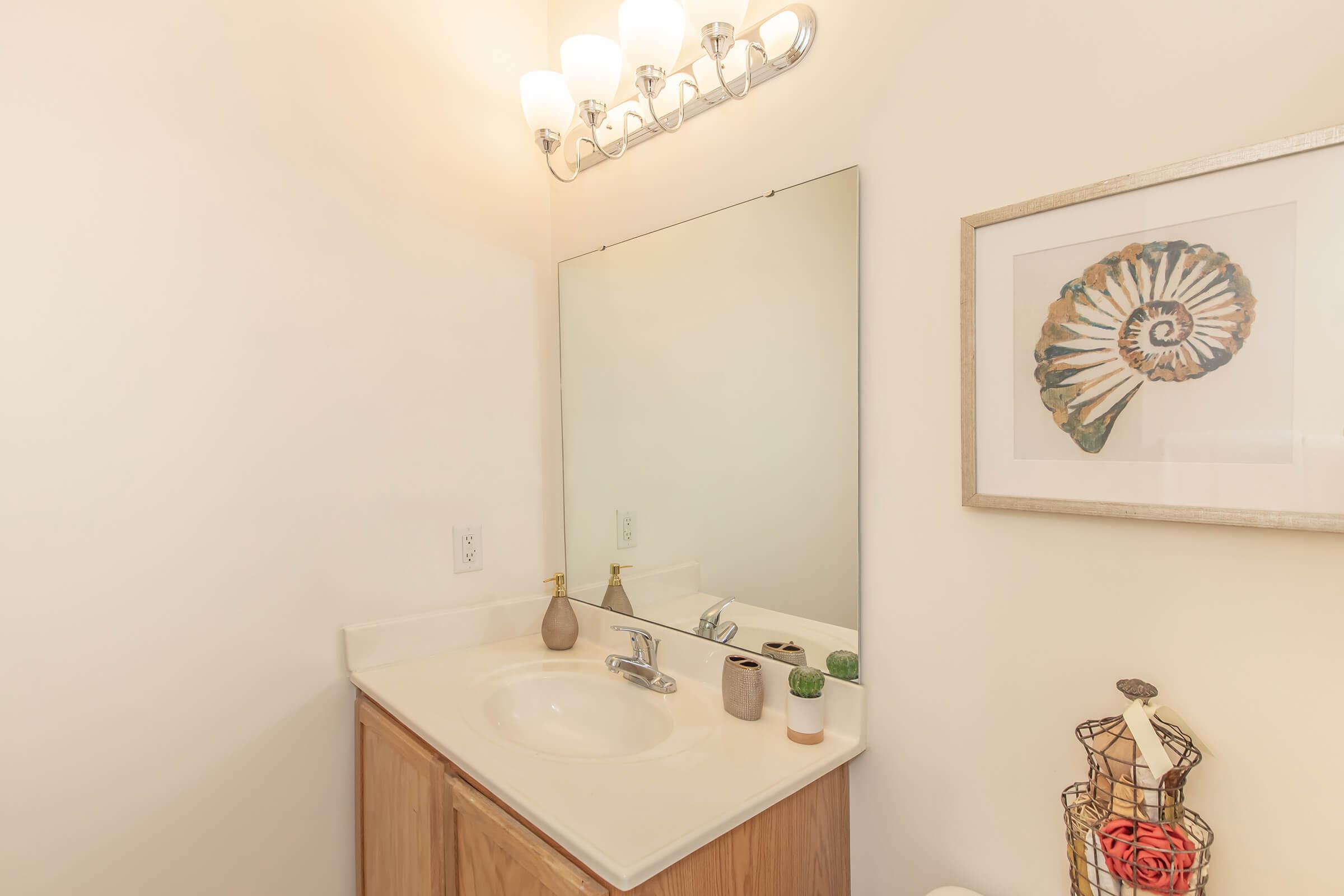 a white sink sitting under a mirror