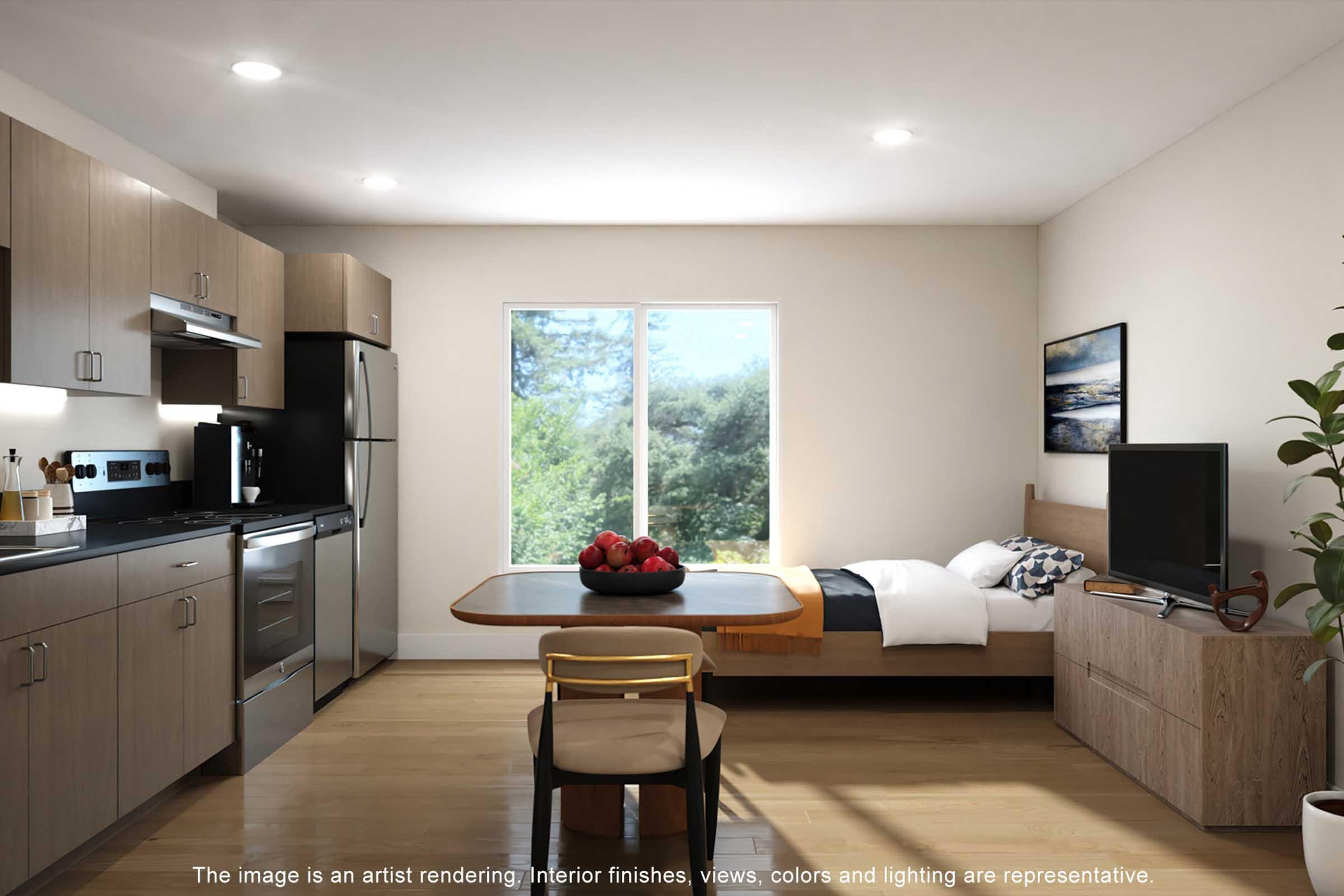 A modern studio apartment interior featuring a kitchen with stainless steel appliances and wooden cabinetry. A dining table is set near a window with a view of greenery. The sleeping area includes a bed and a wooden media console. Natural light fills the space, enhancing the neutral color palette.