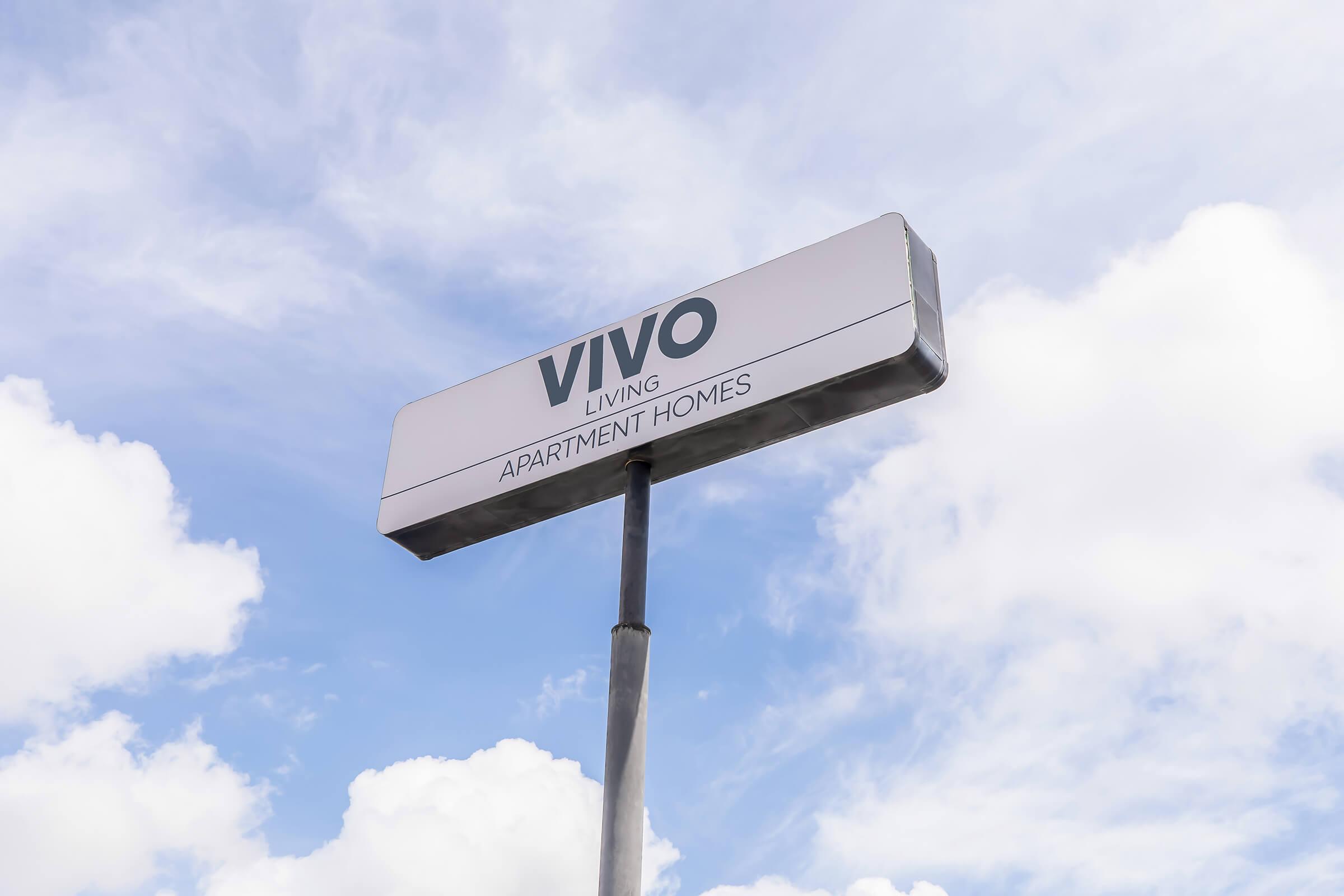 Sign for "Vivo Living Apartment Homes" against a backdrop of blue sky with scattered white clouds.