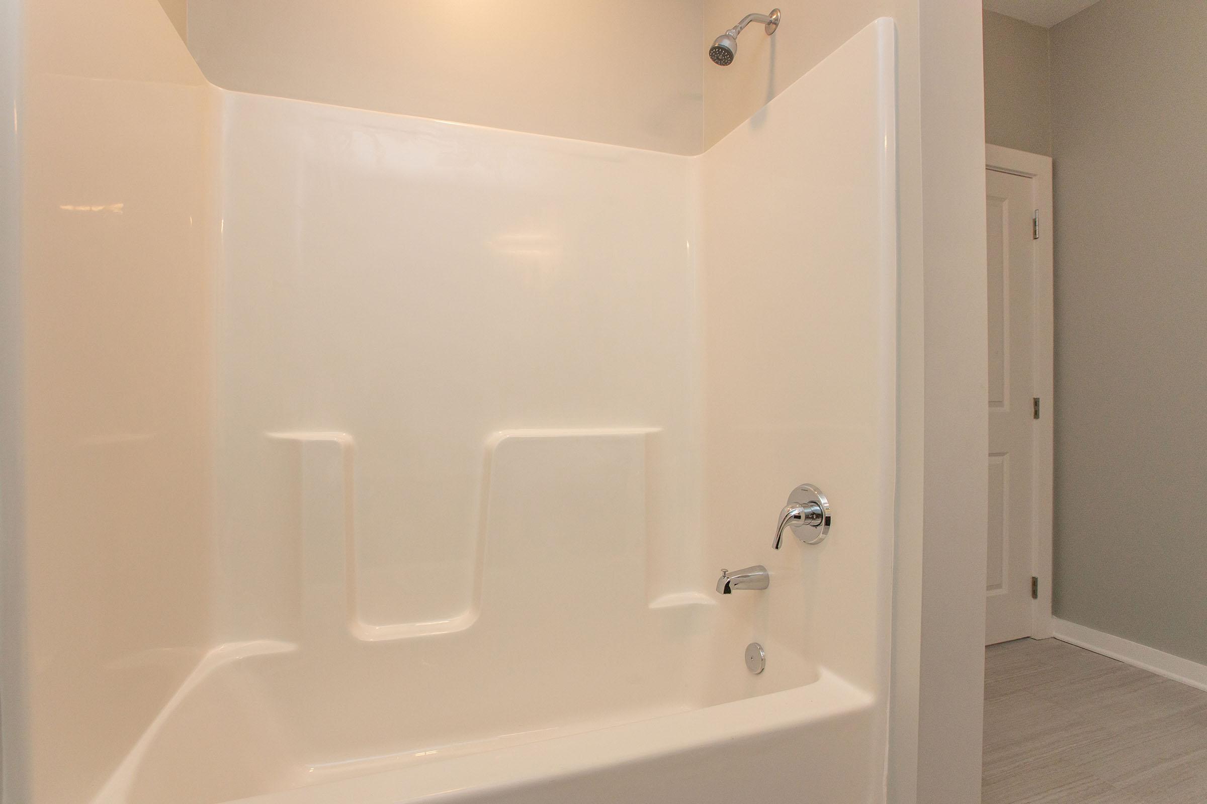 a close up of a white tub sitting next to a shower