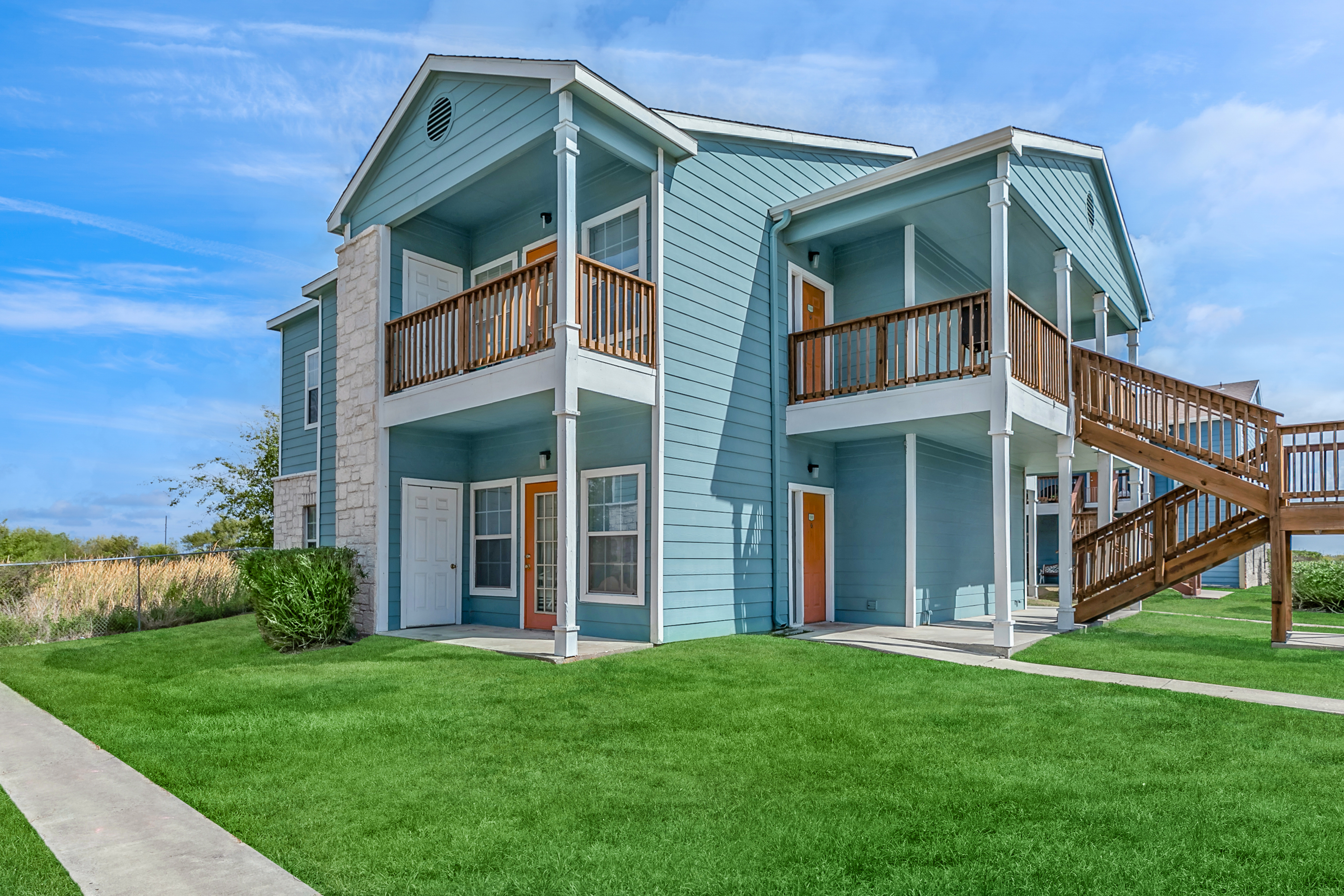 Exterior building 2 stories with view of patio open greenspace and balconies  Portside Villas Apts