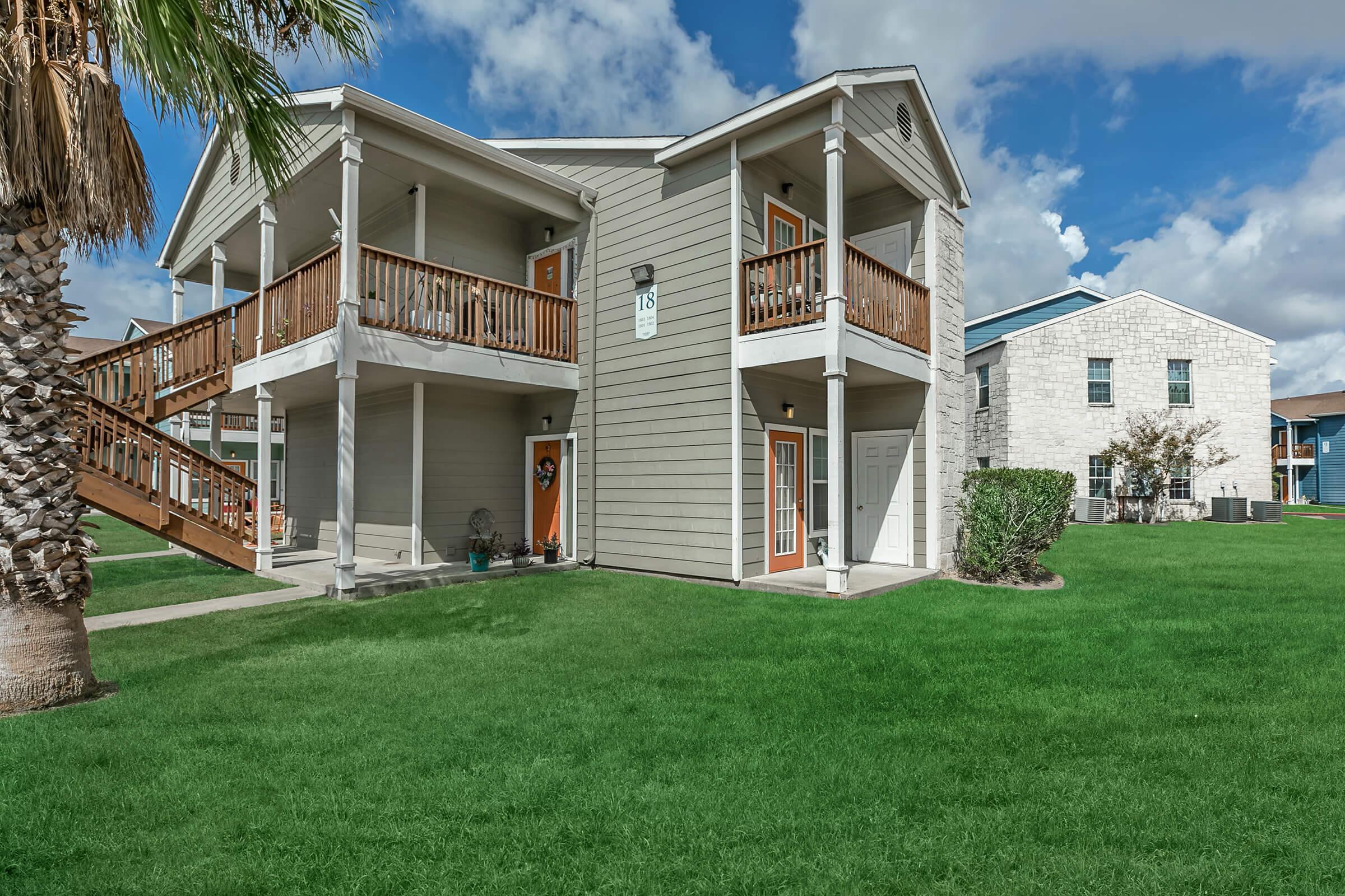 Exterior building 2 stories with view of patio open greenspace and balconies  Portside Villas Apts