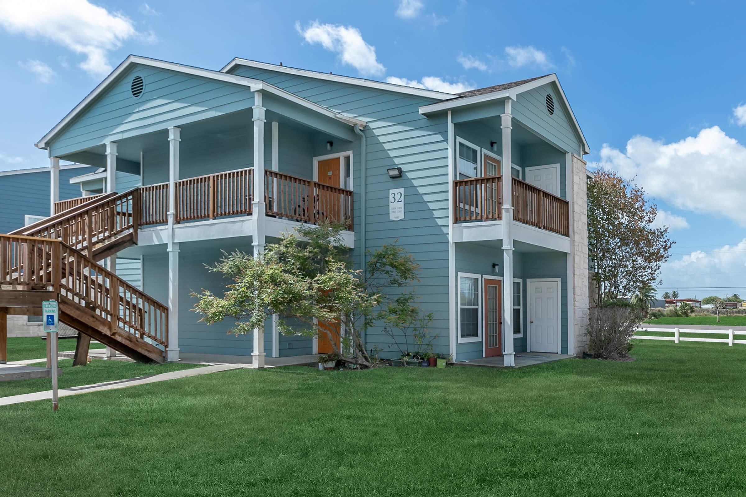 Exterior building 2 stories with view of patio open greenspace and balconies  Portside Villas Apts