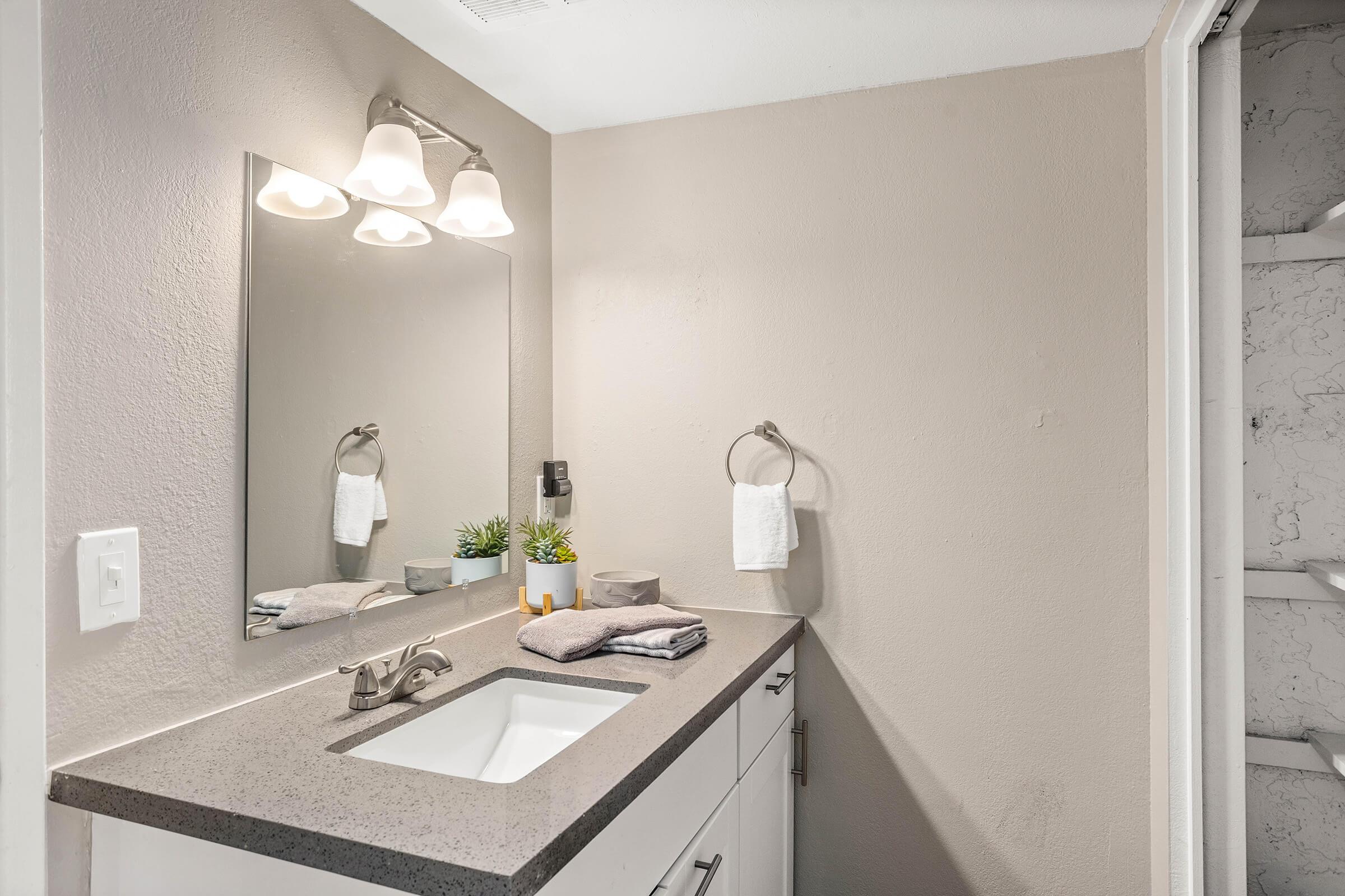 renovated bathroom with mirrored vanity set and grey quartz counter tops