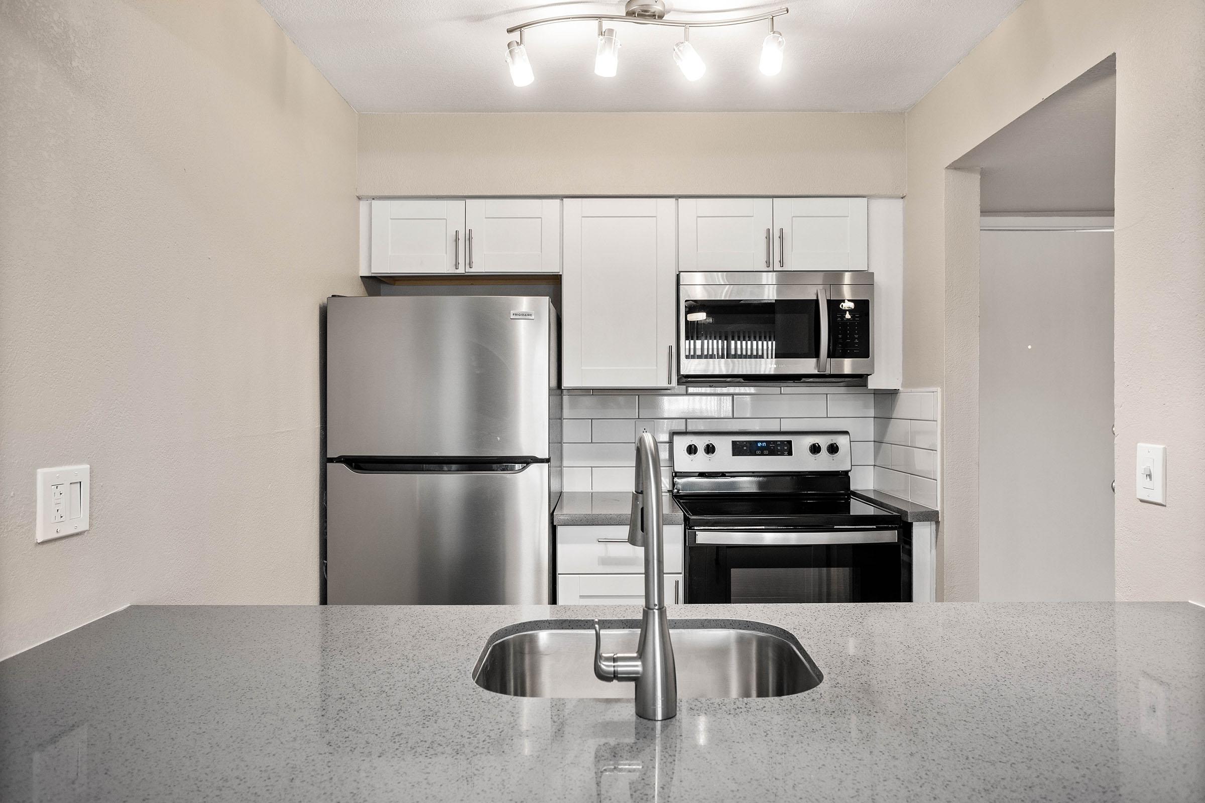 Renovated kitchen with large quartz island and stainless steel appliances
