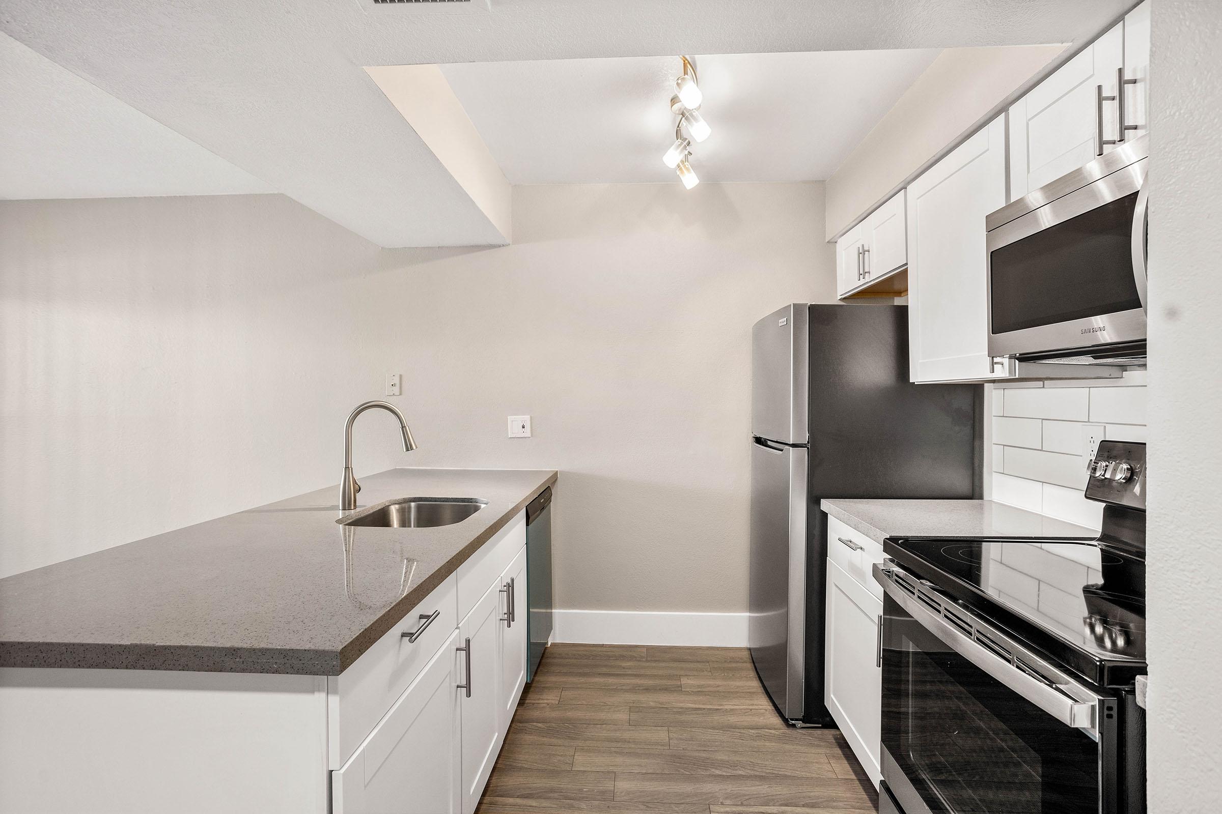 Renovated kitchen with white cabinets, grey counter tops, and stainless steel appliances