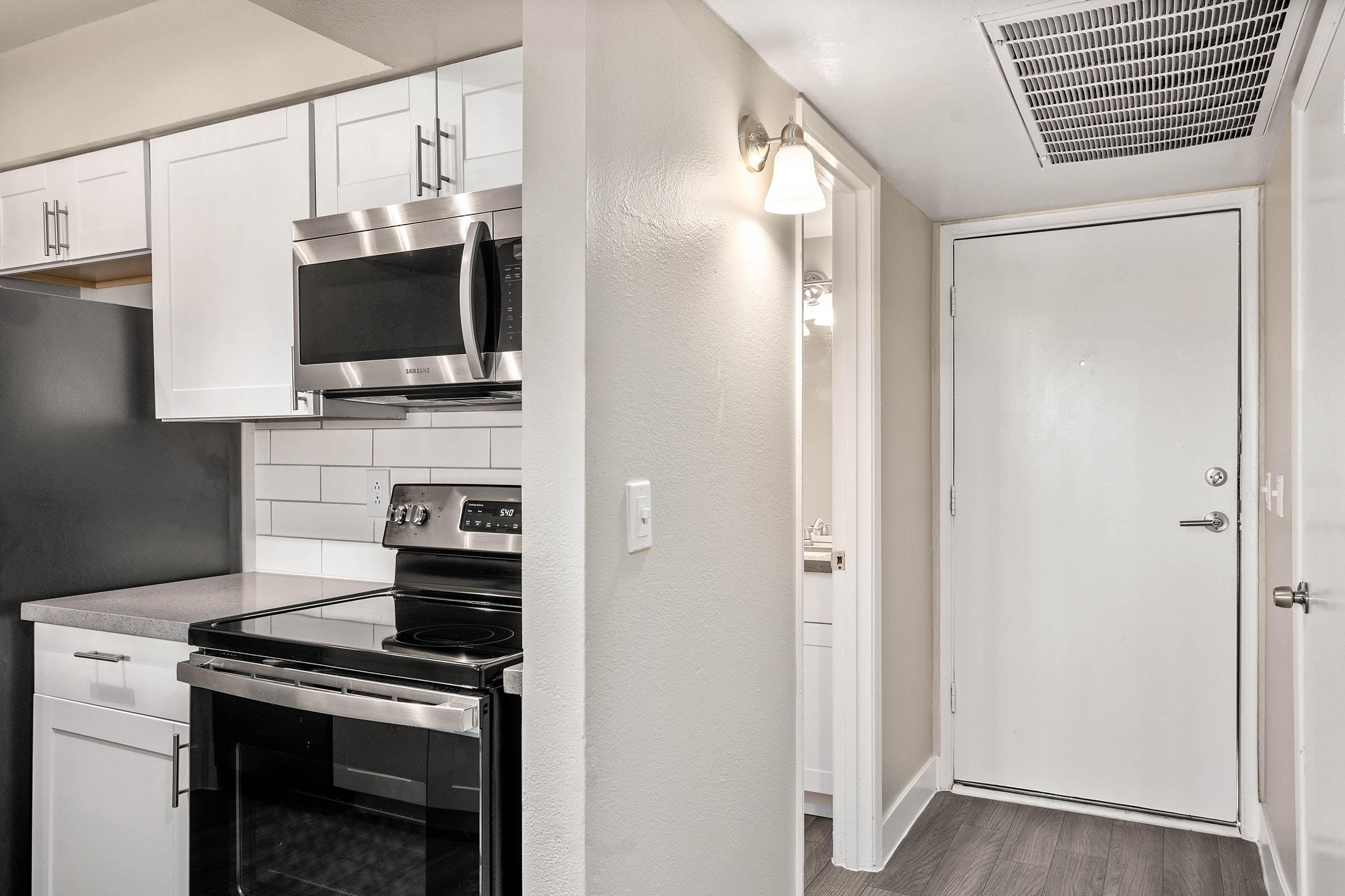 Studio apartment entryway next to a bathroom and a renovated kitchen