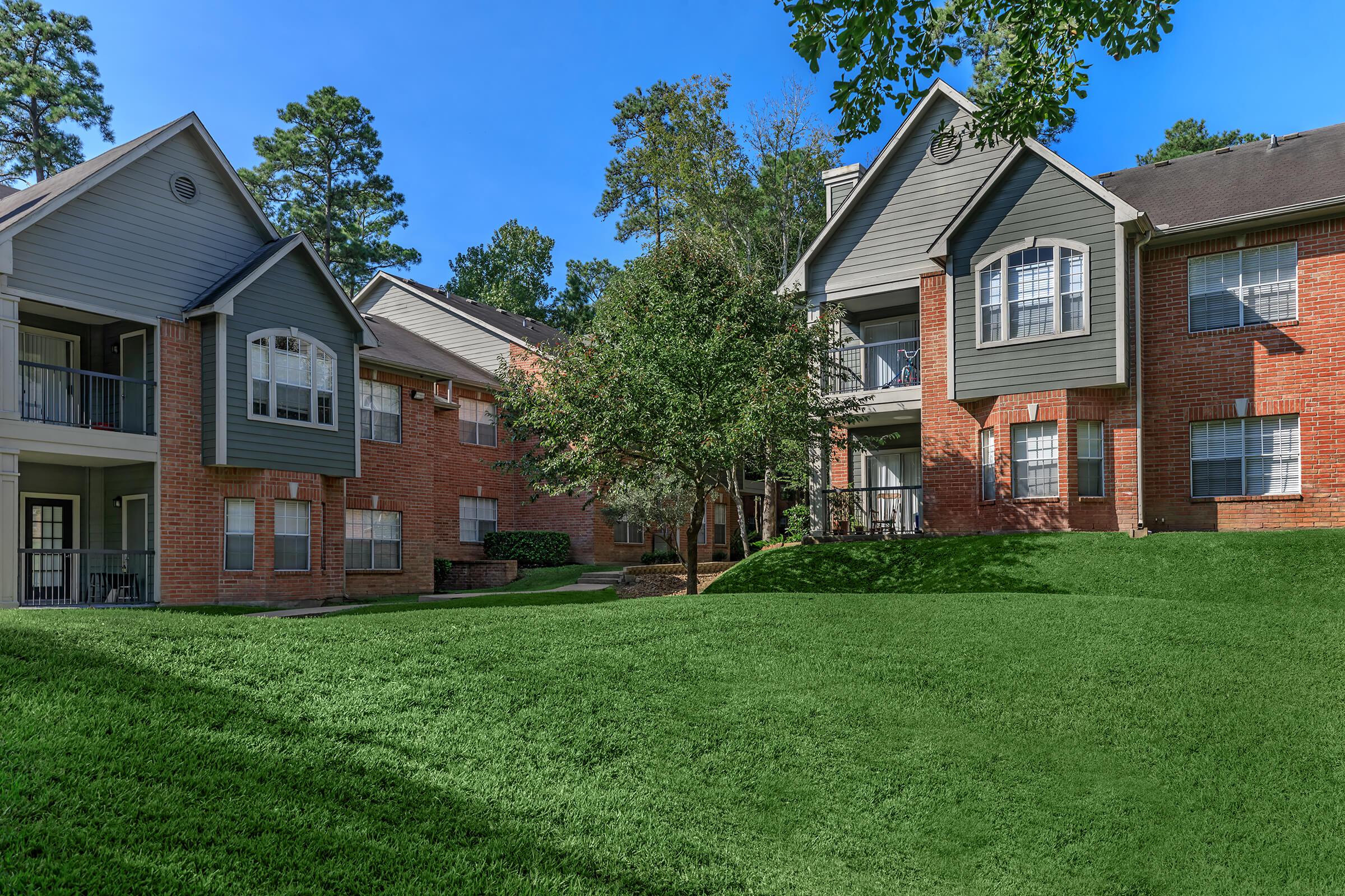 a large brick building with grass in front of a house