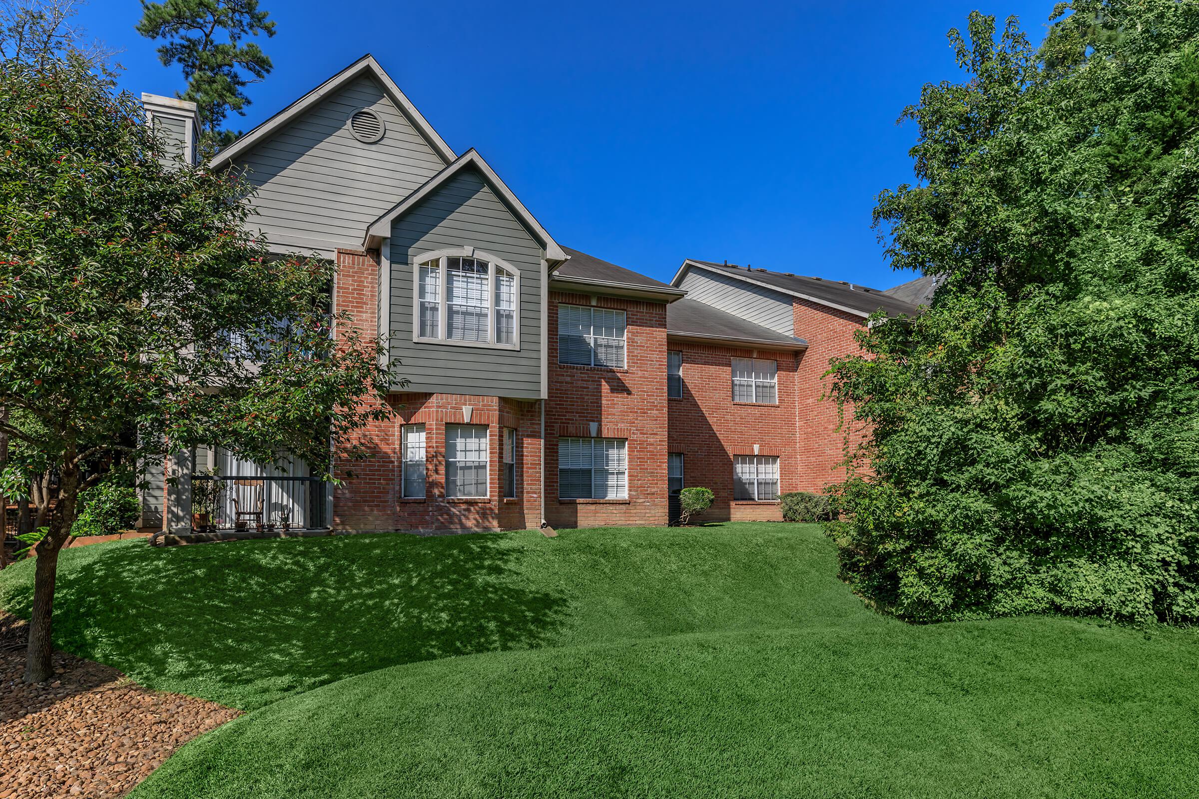 a large brick building with grass in front of a house