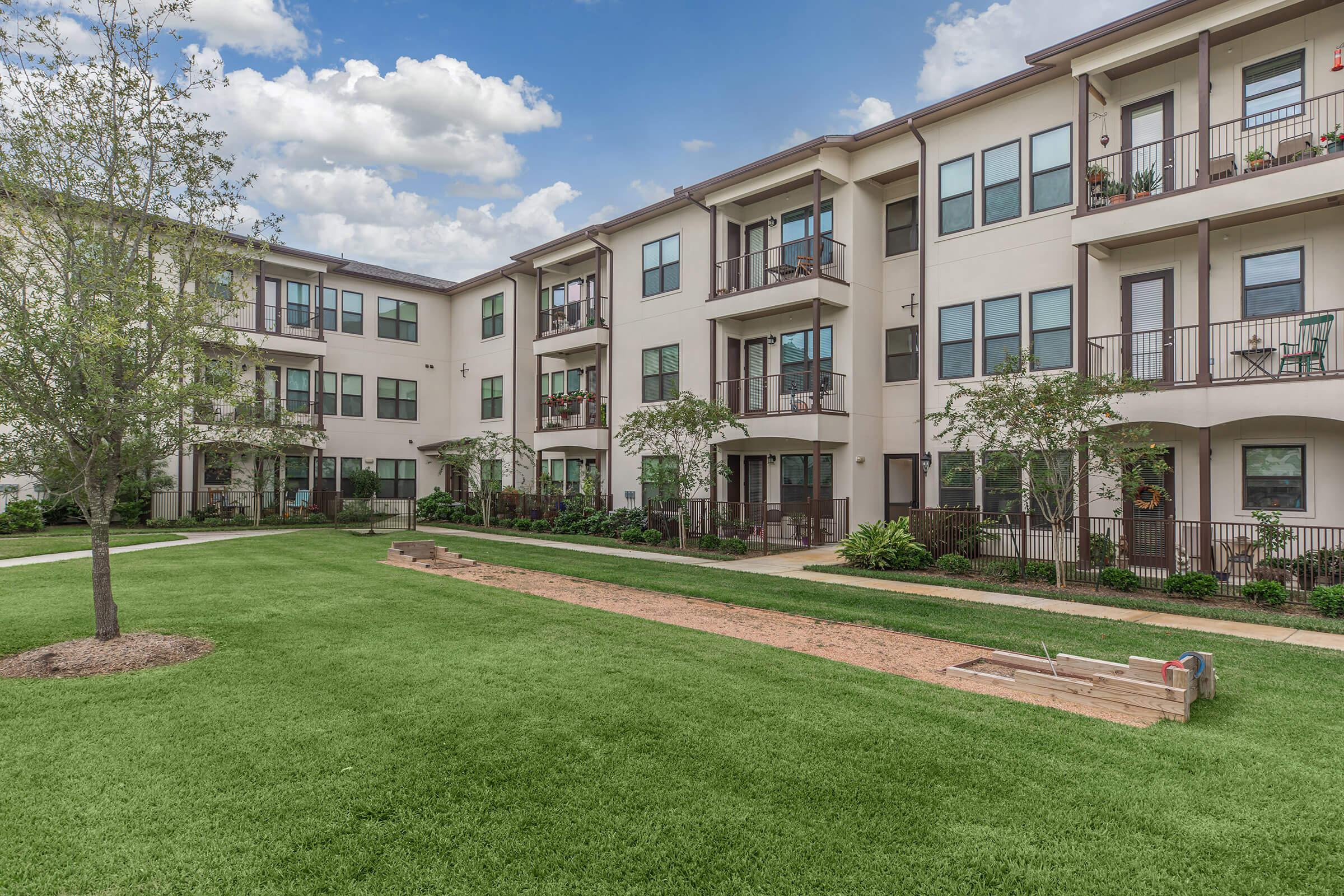 the grounds at ivy point kingwood senior living apartments featuring a putting green and view of the apartment exteriors