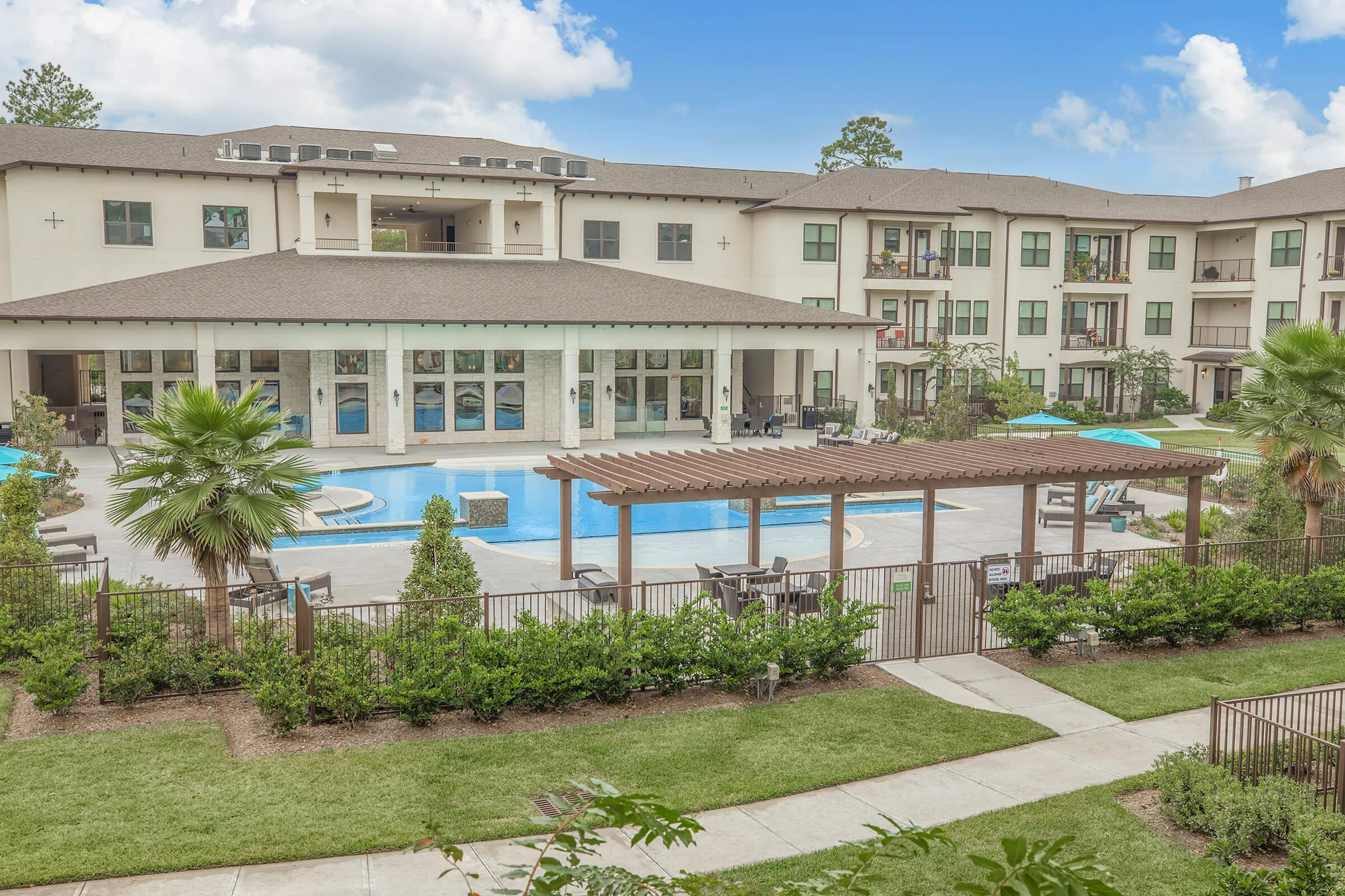 the grounds at ivy point kingwood senior living apartments featuring a putting green and view of the apartment exteriors