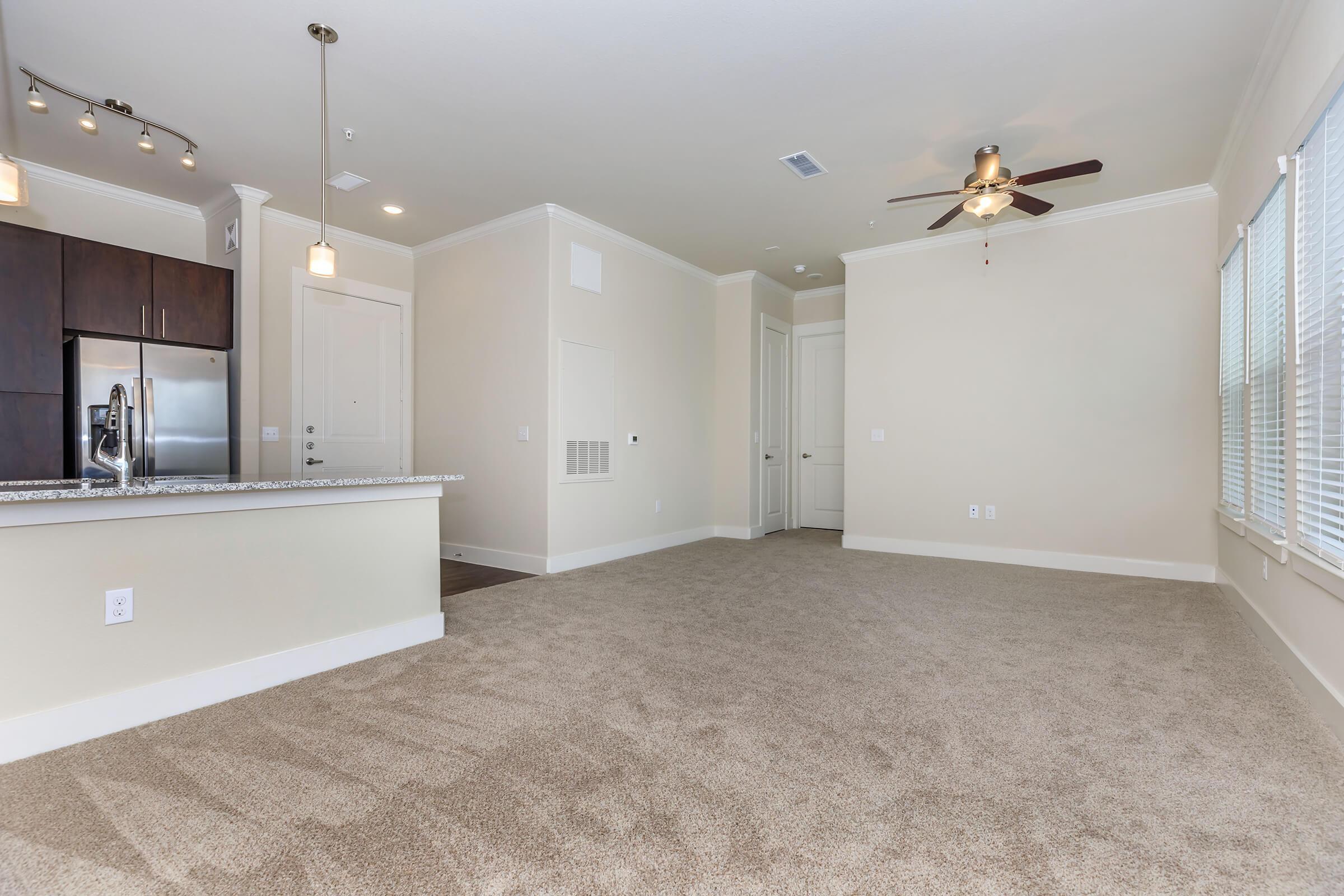 empty room at ivy point kingwood senior living apartments in kingwood tx featuring carpeted flooring and a view of the kitchen