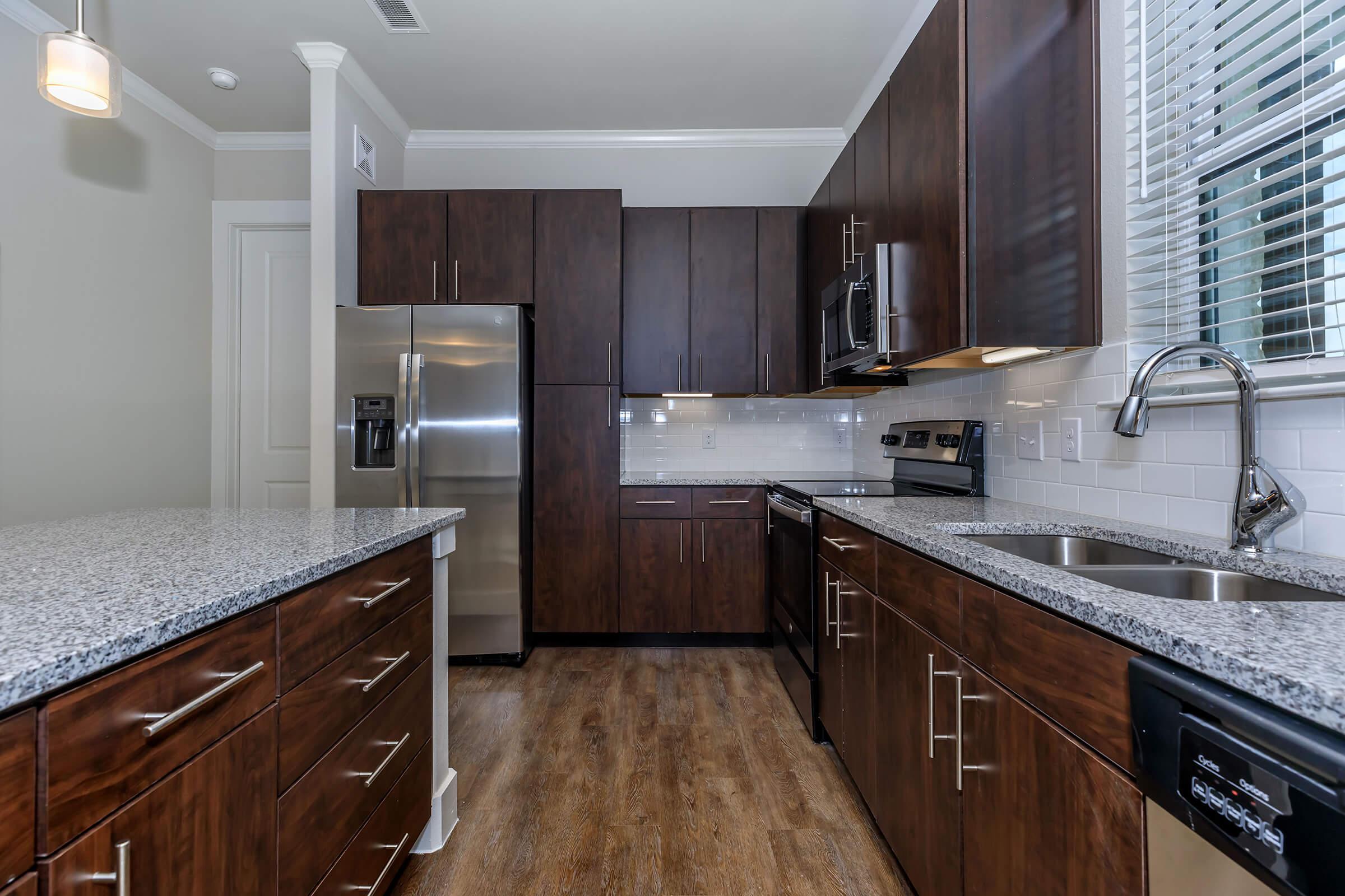 kitchen at ivy point kingwood senior living apartments in kingwood tx featuring wood grain flooring and granite counters