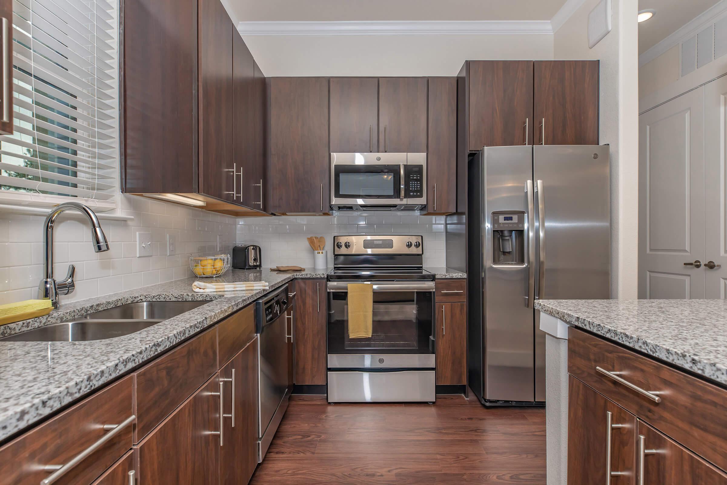 kitchen at ivy point kingwood senior living apartments in kingwood tx featuring wood grain flooring and granite counters