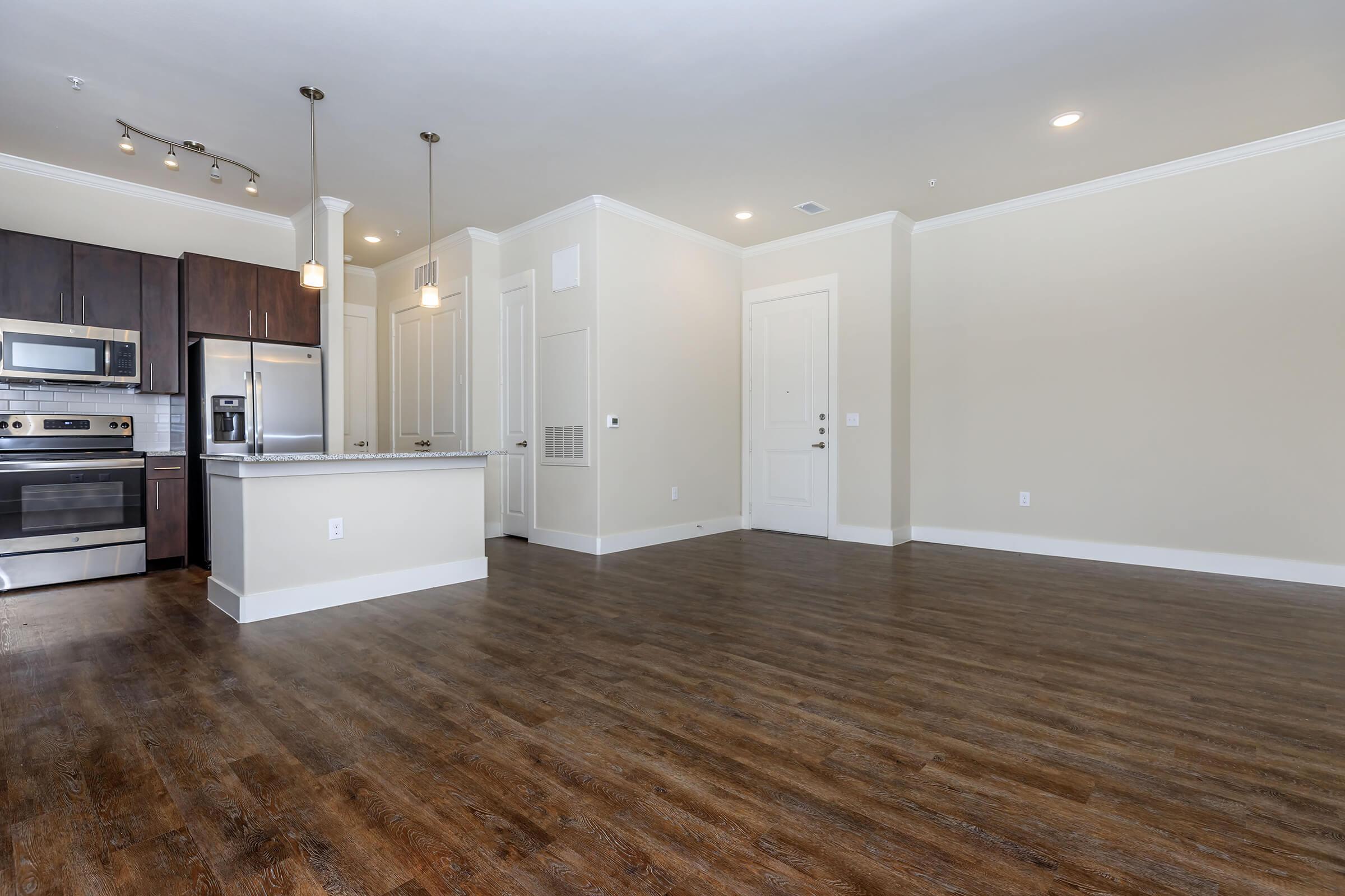 empty room at ivy point kingwood senior living apartments in kingwood tx featuring wood grain flooring and a view of the kitchen