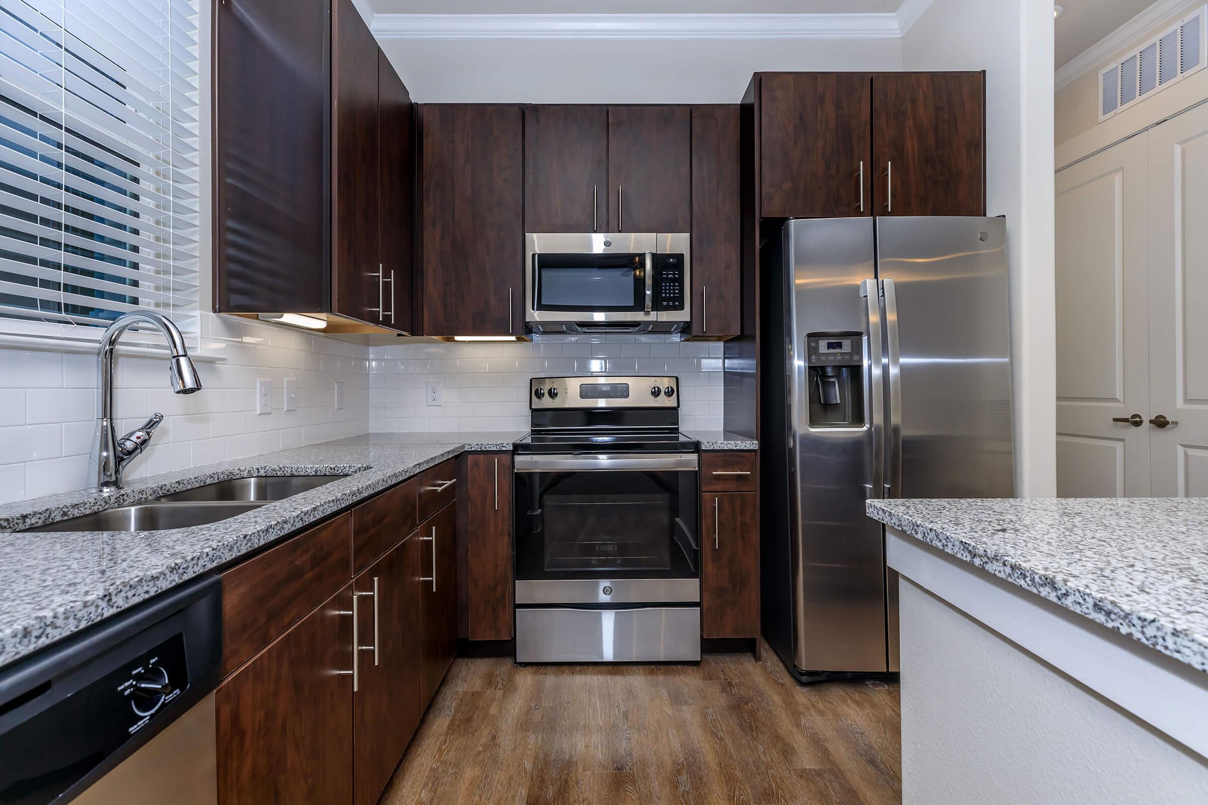 kitchen at ivy point kingwood senior living apartments in kingwood tx featuring wood grain flooring and granite counters