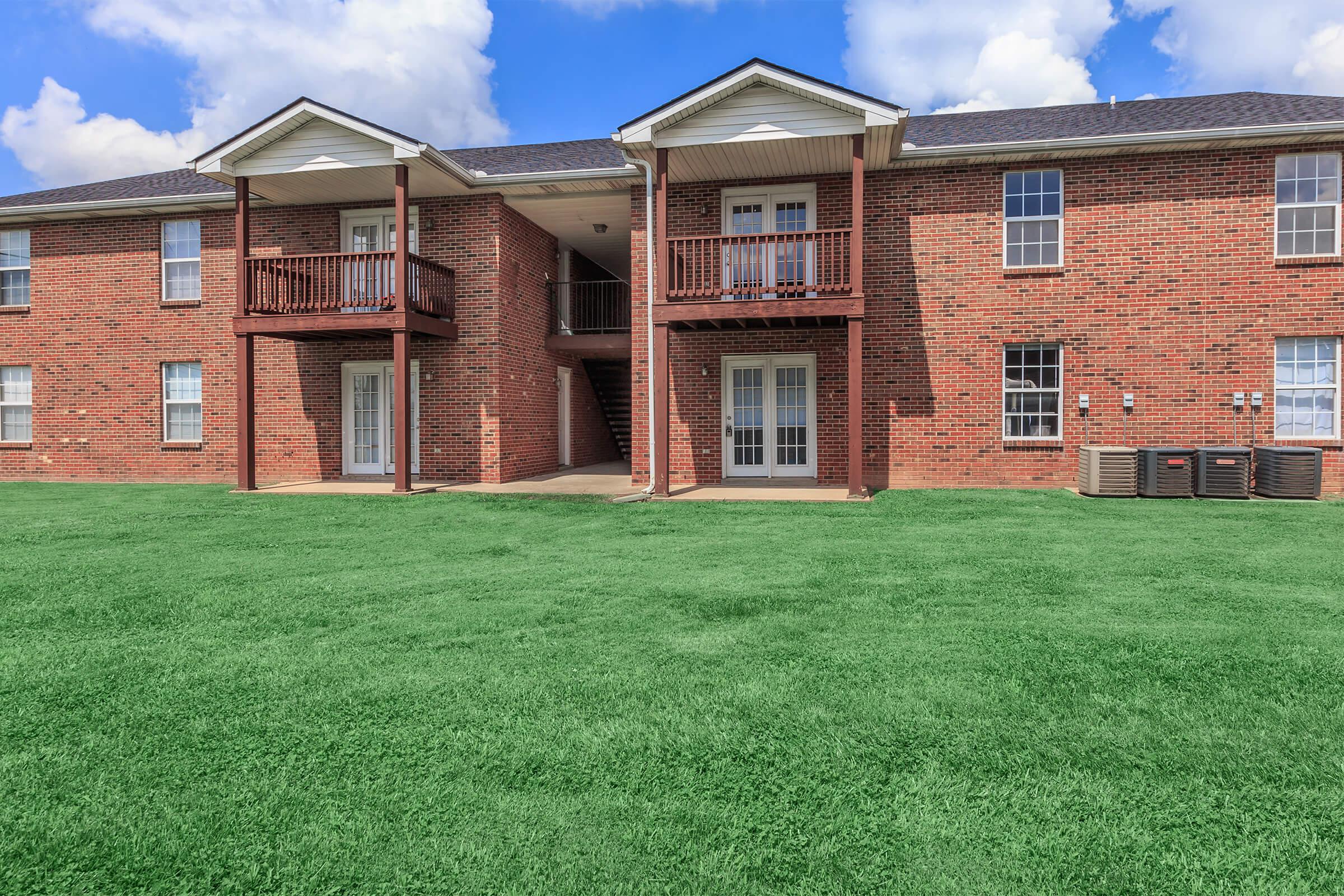 a large brick building with green grass in front of a house