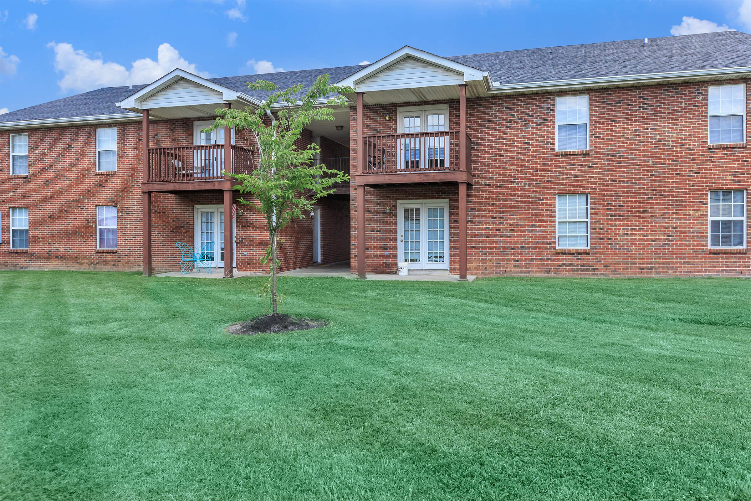 a large brick building with grass in front of a house