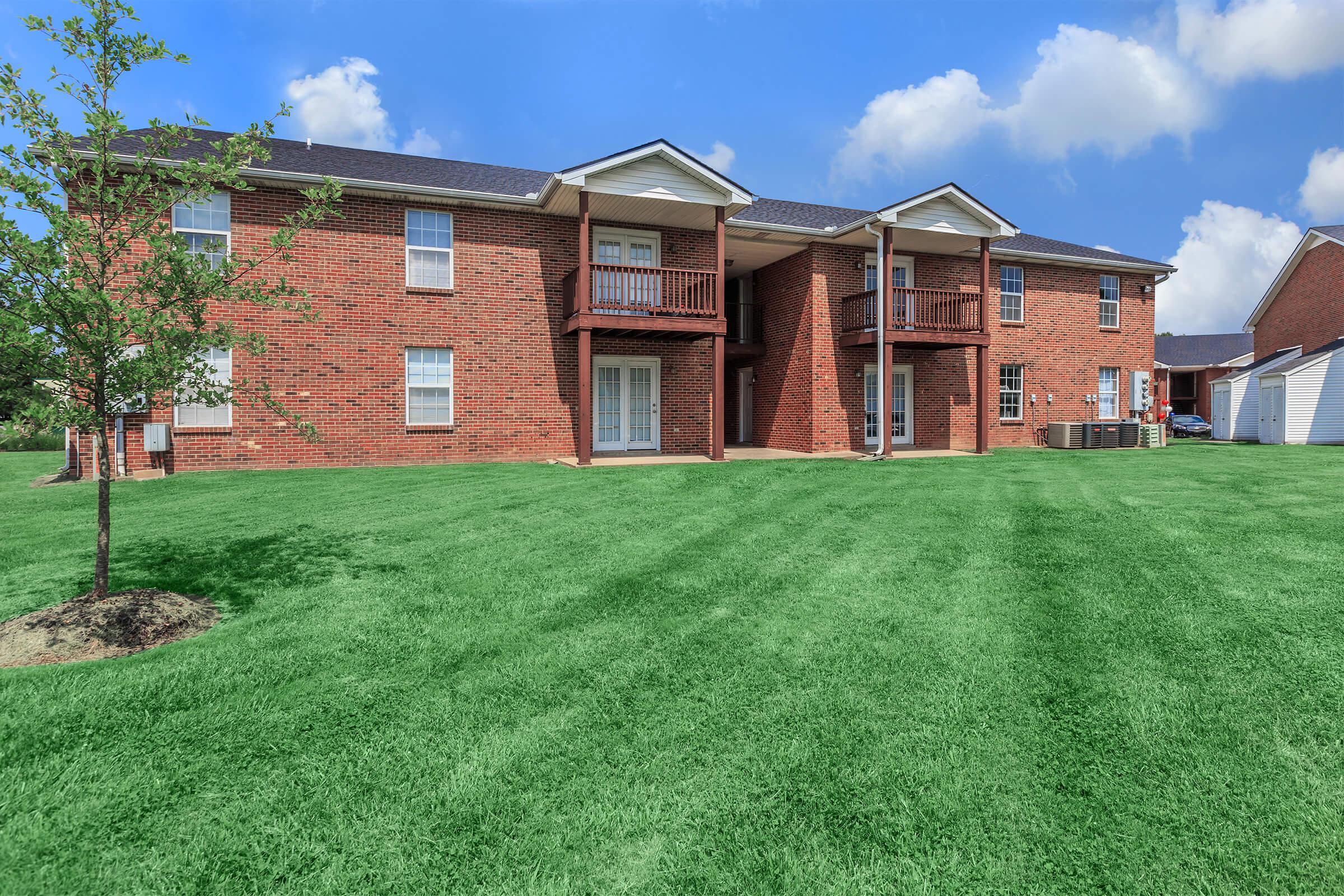 a large brick building with green grass in front of a house