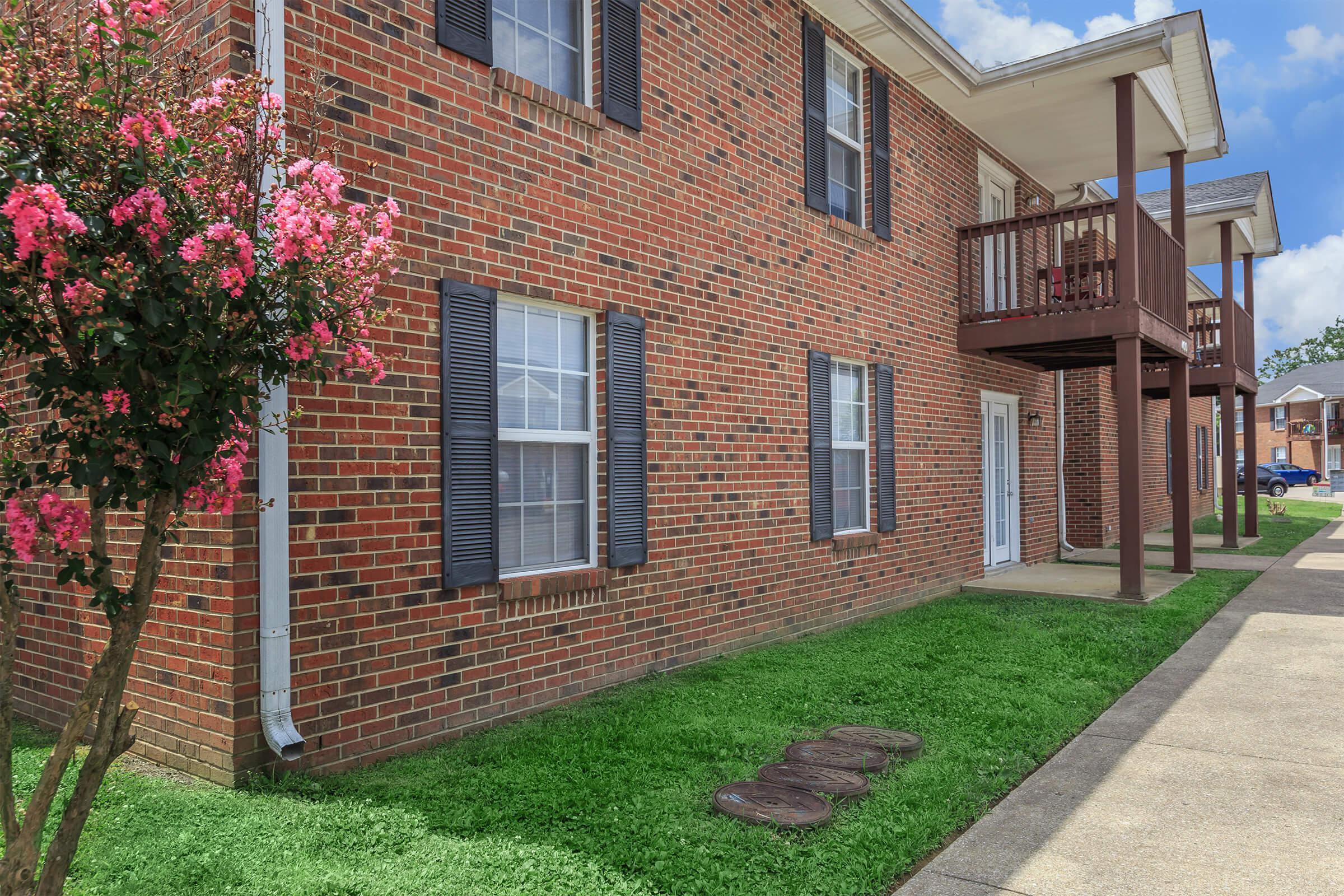 a large brick building with grass in front of a house