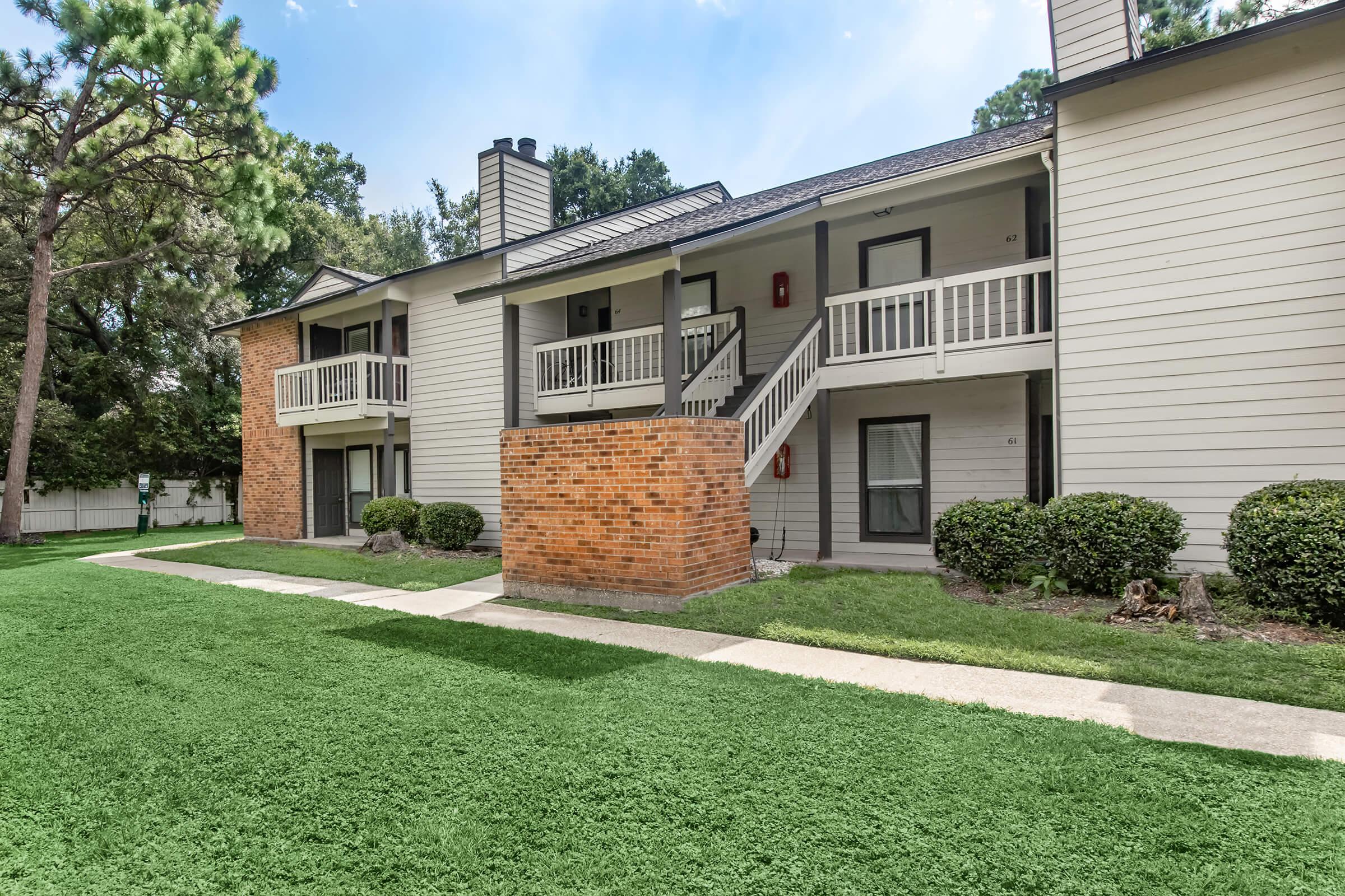 a house with a lawn in front of a brick building