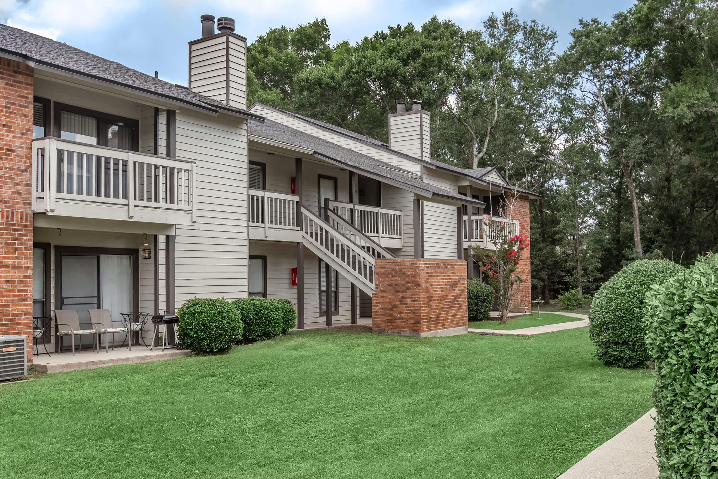 a large brick building with grass in front of a house