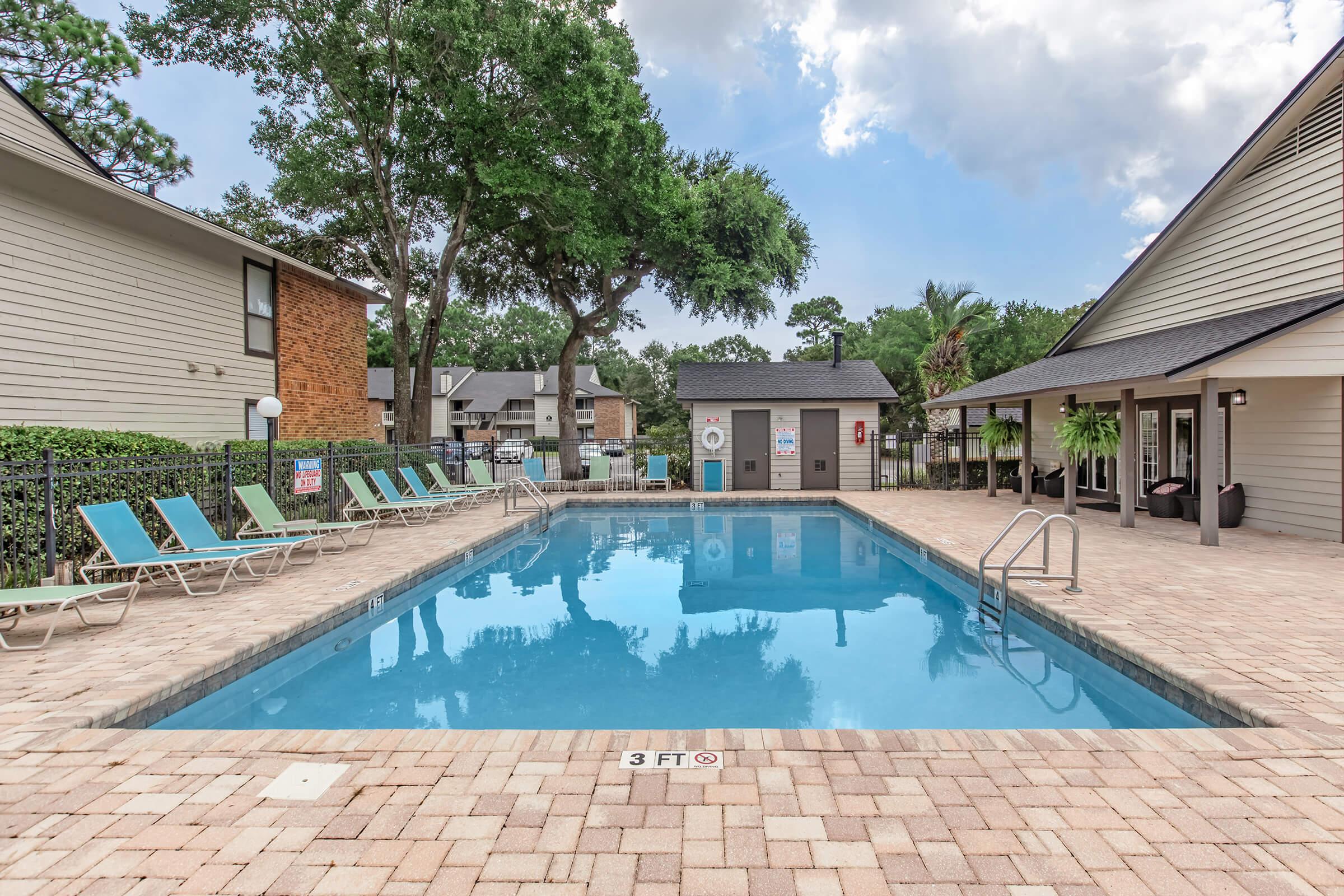 a house with a pool in front of a brick building