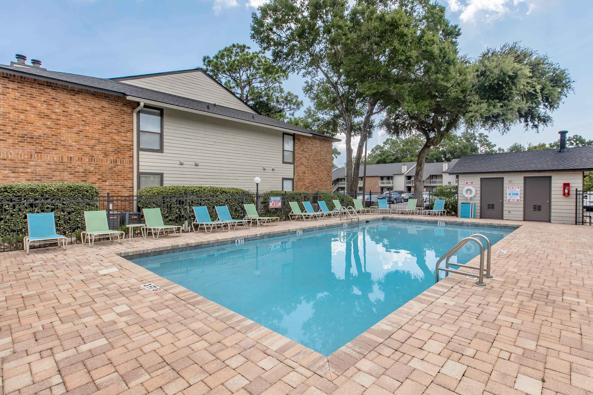 a house with a pool in front of a brick building