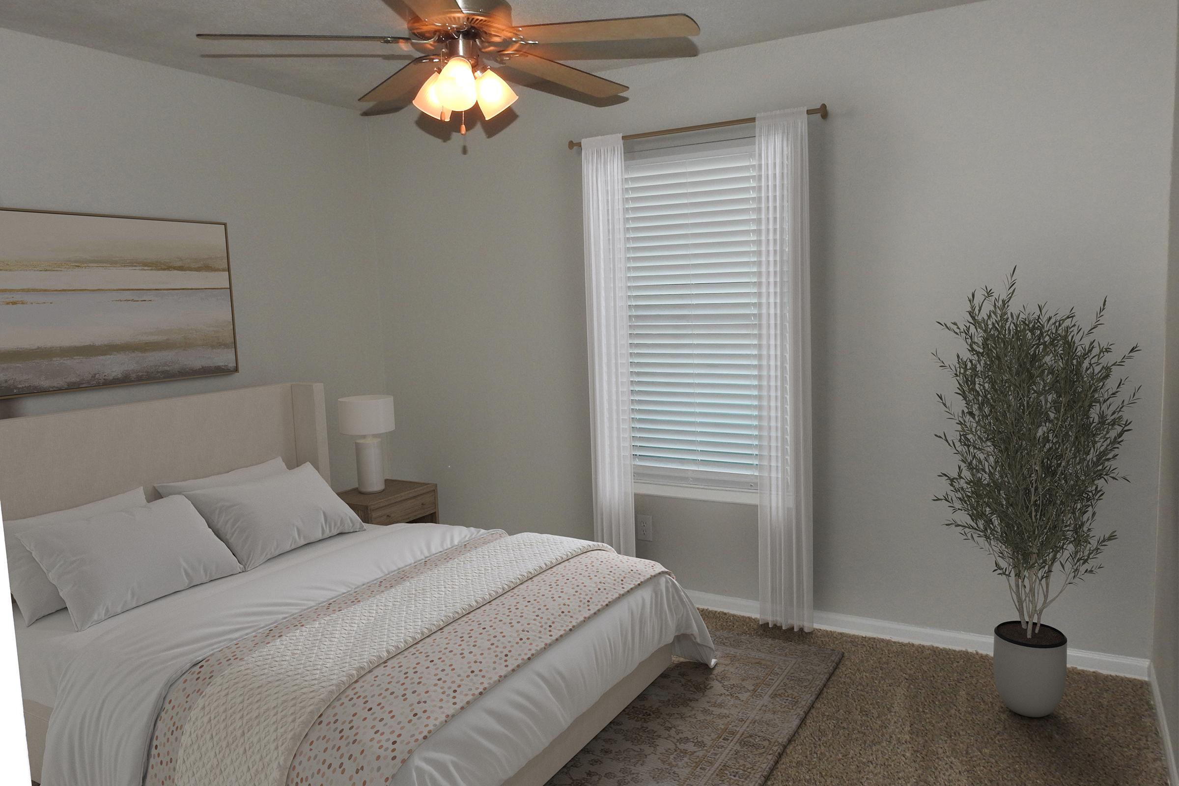 A cozy bedroom featuring a neatly made bed with white linens and decorative pillows. There's a bedside table with a lamp, a large window with white curtains allowing natural light, and a potted plant in the corner. The walls are painted a soft gray, and a piece of art hangs above the bed.