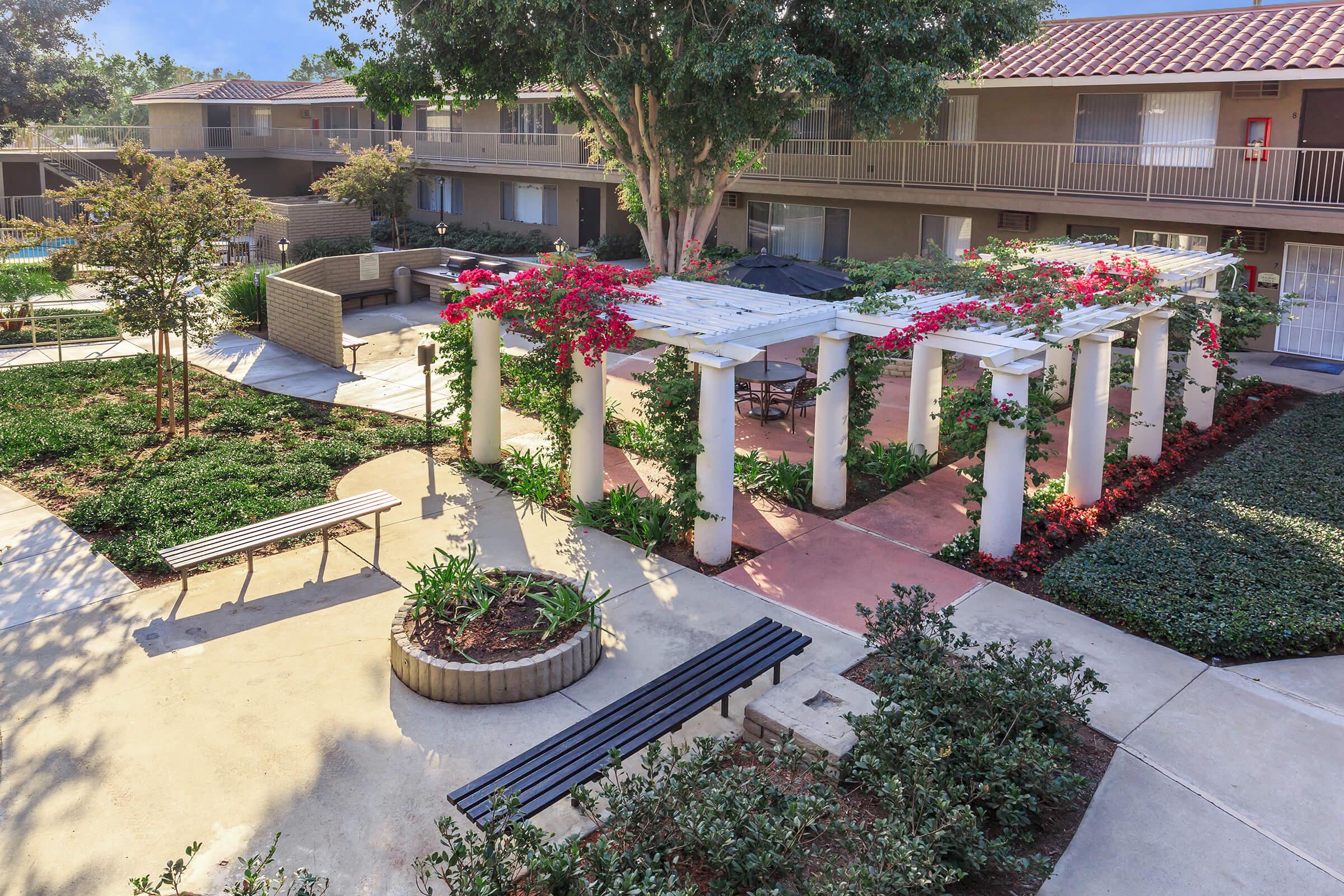 Camino Pueblo and El Rancho Apartment Homes courtyard with white arbors and flowers
