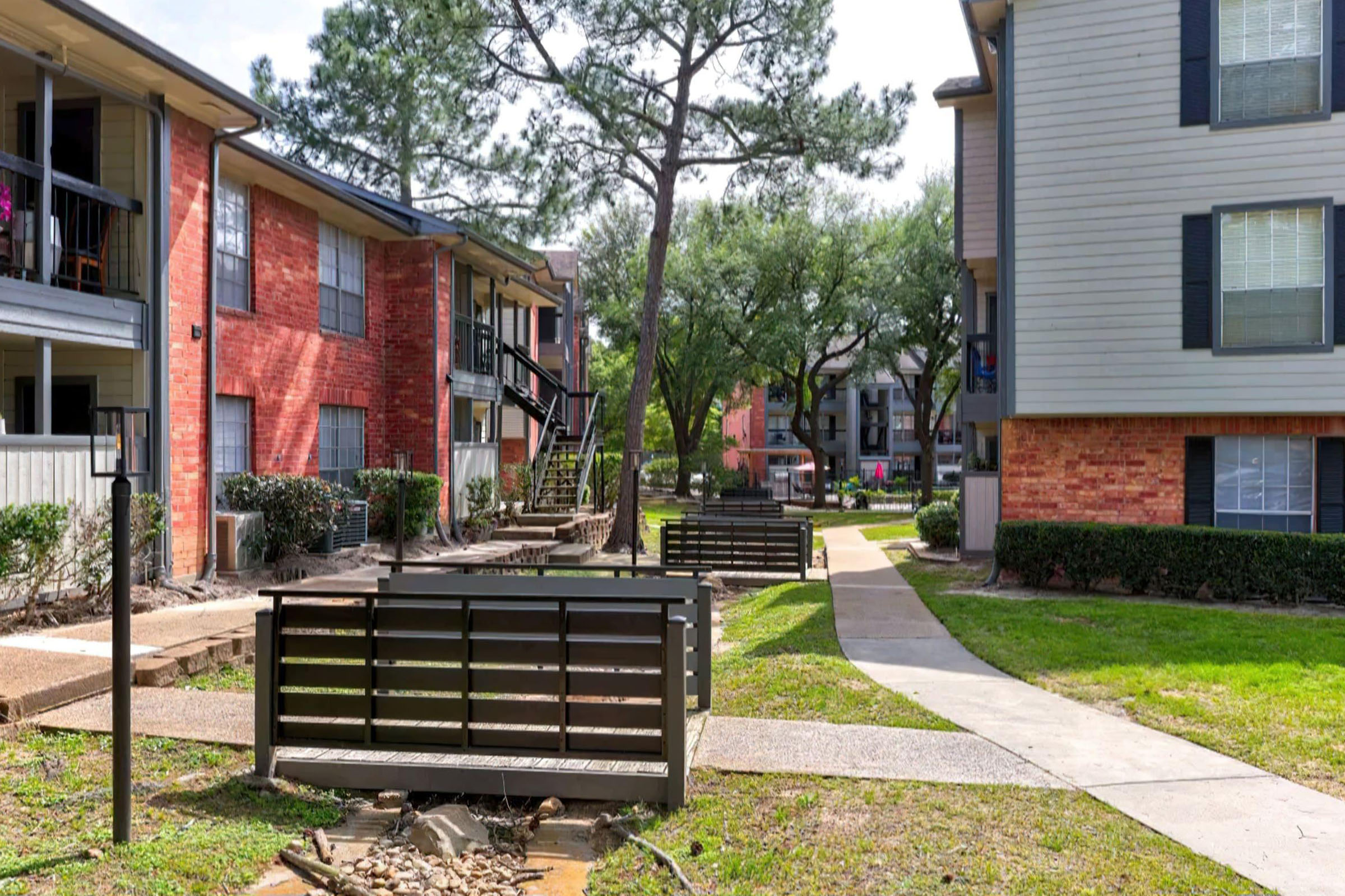 an empty park bench sitting in front of a brick building