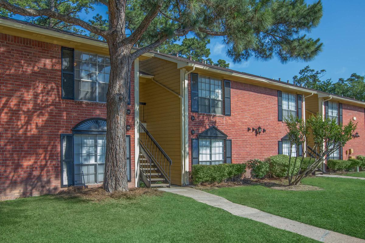 a house with a lawn in front of a brick building