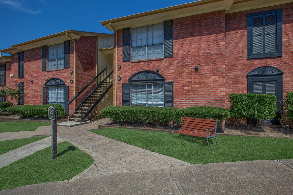 a large brick building with grass in front of a house