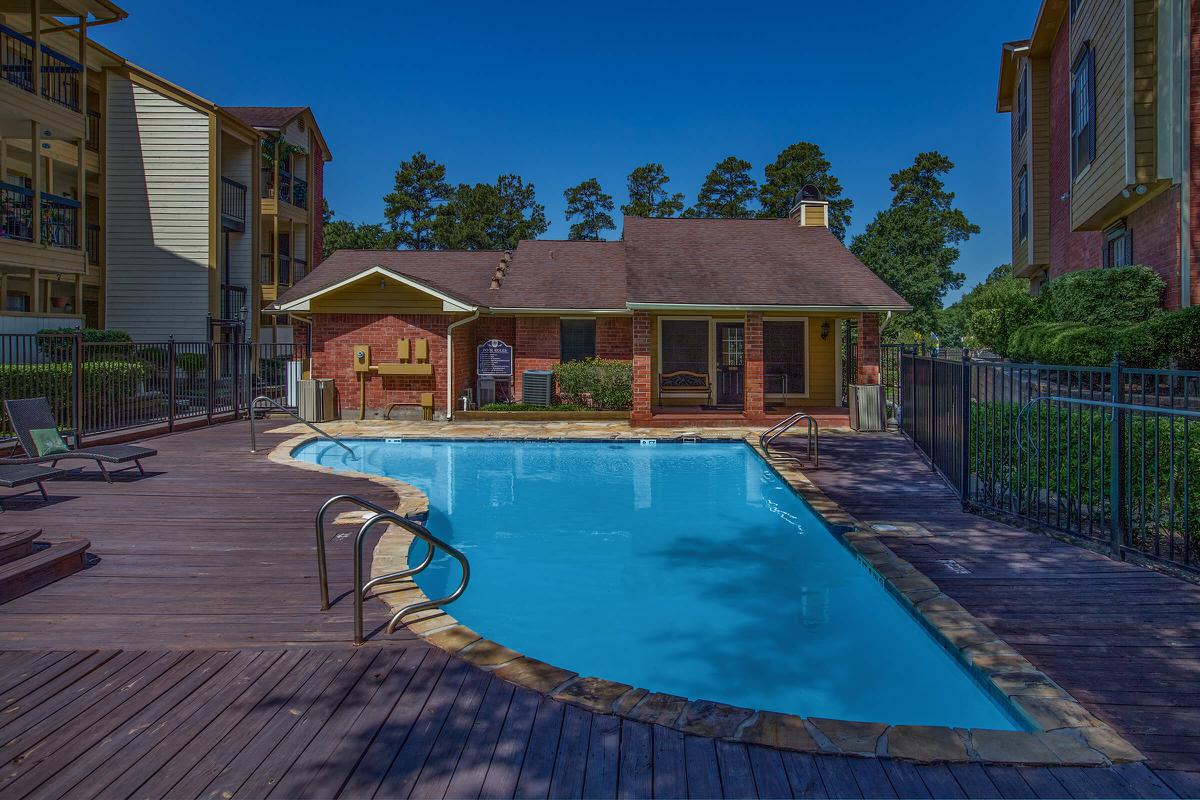 a house with a pool in front of a brick building