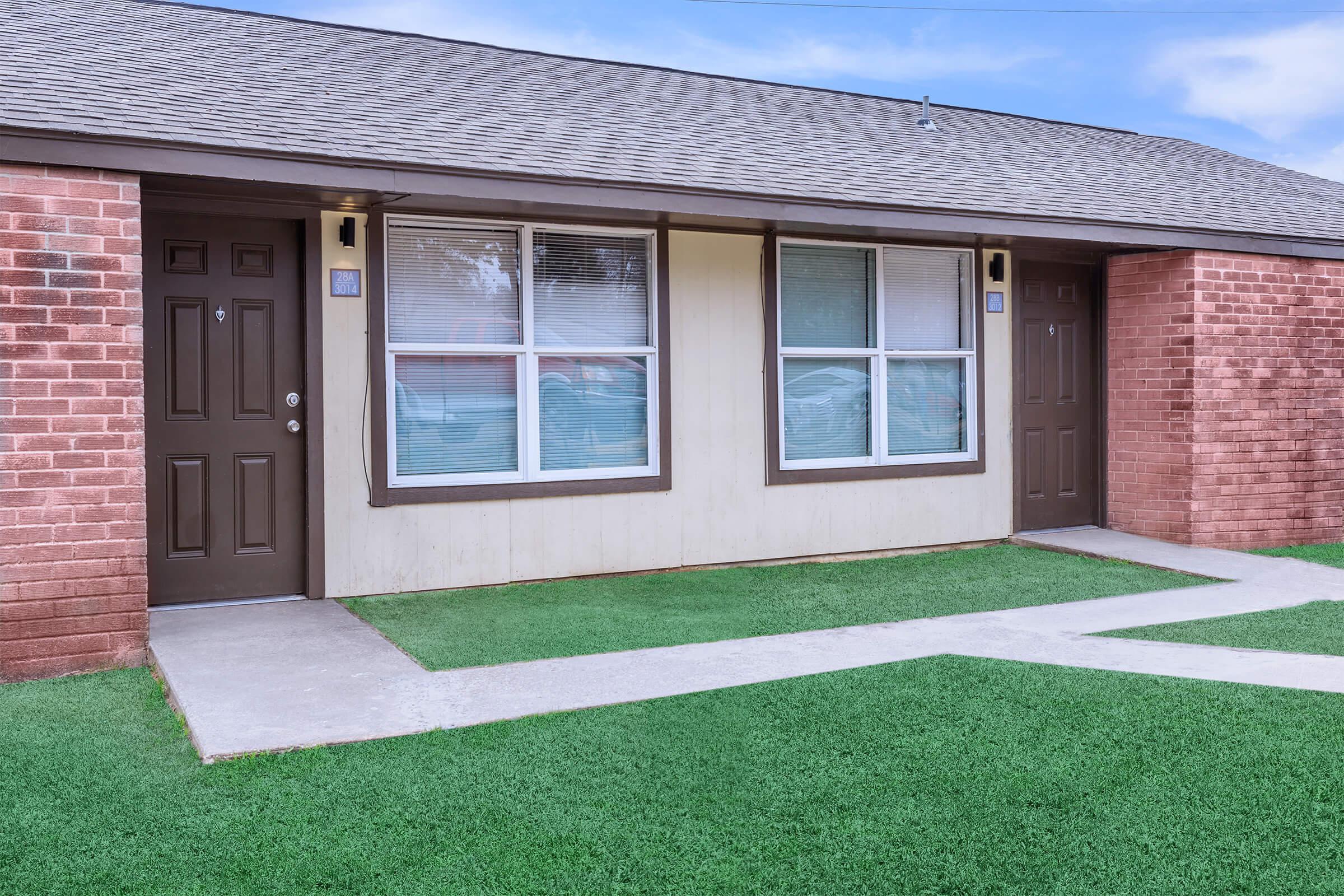 a house with a lawn in front of a brick building