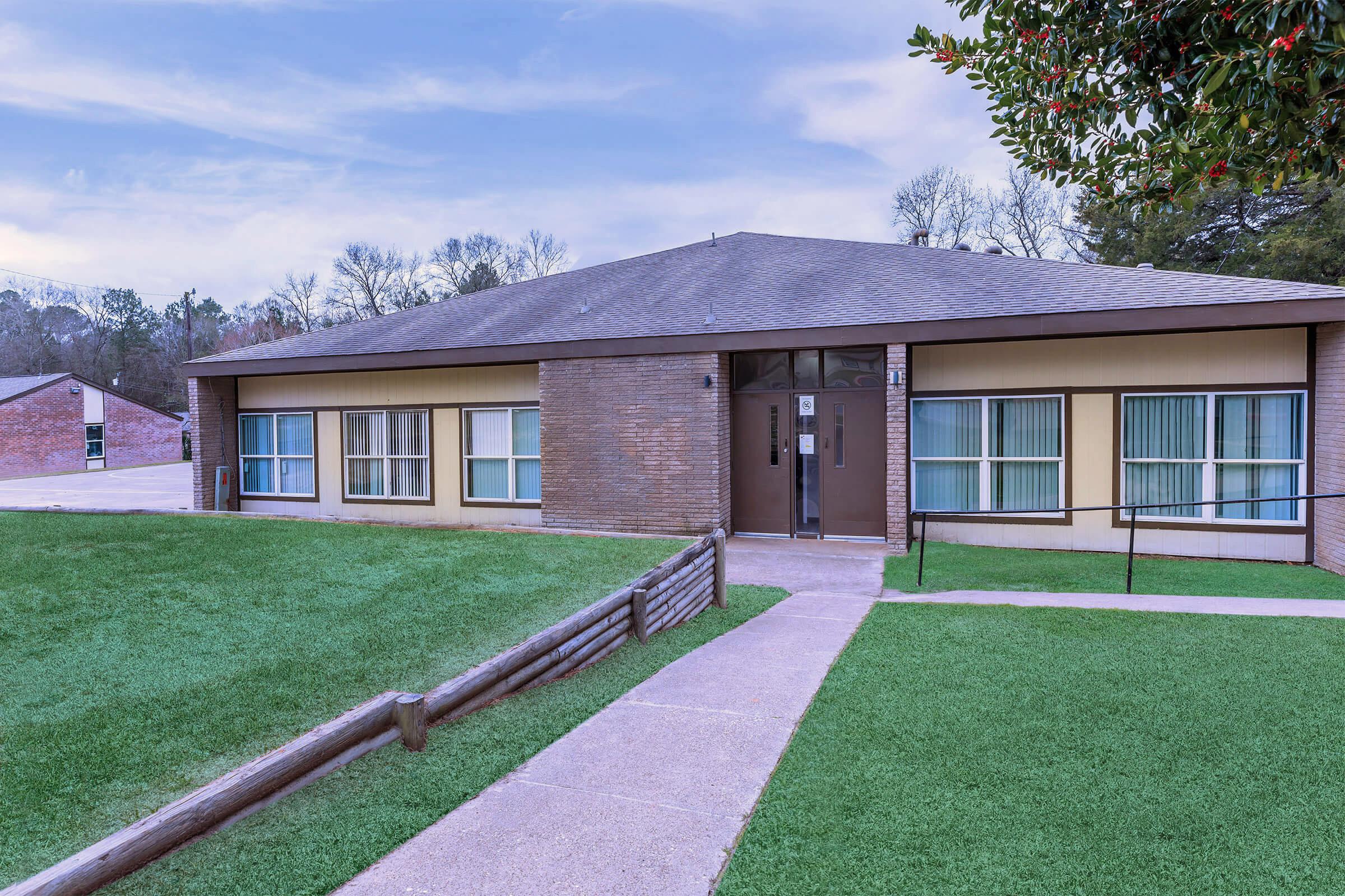 a house with a lawn in front of a brick building