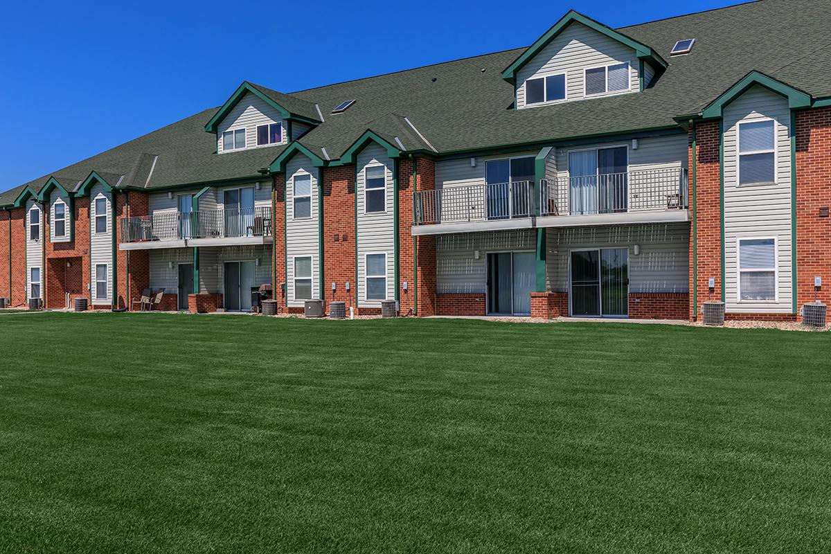 a large brick building with green grass in front of a house