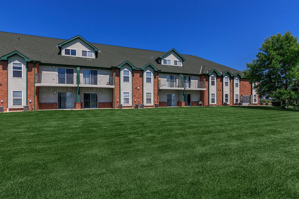 a large brick building with green grass in front of a house