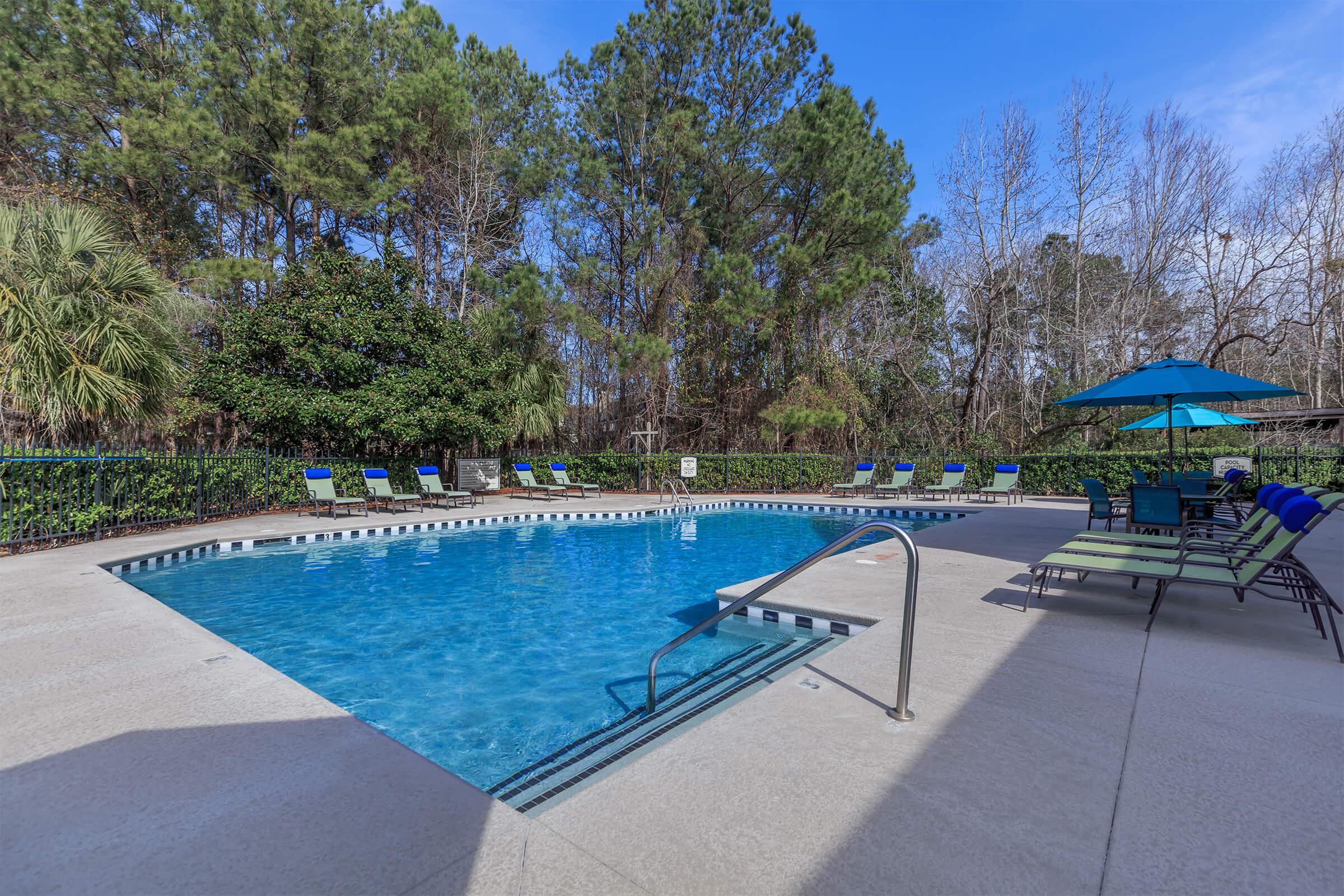 a group of lawn chairs sitting on top of a blue pool of water