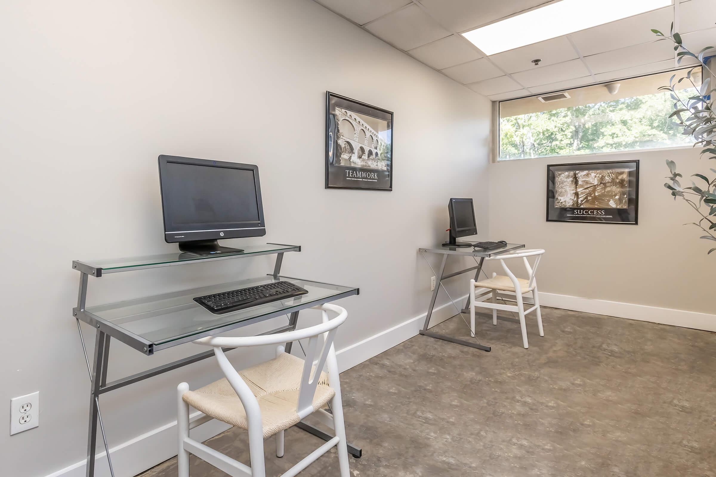 a desk with a computer and a chair in a room