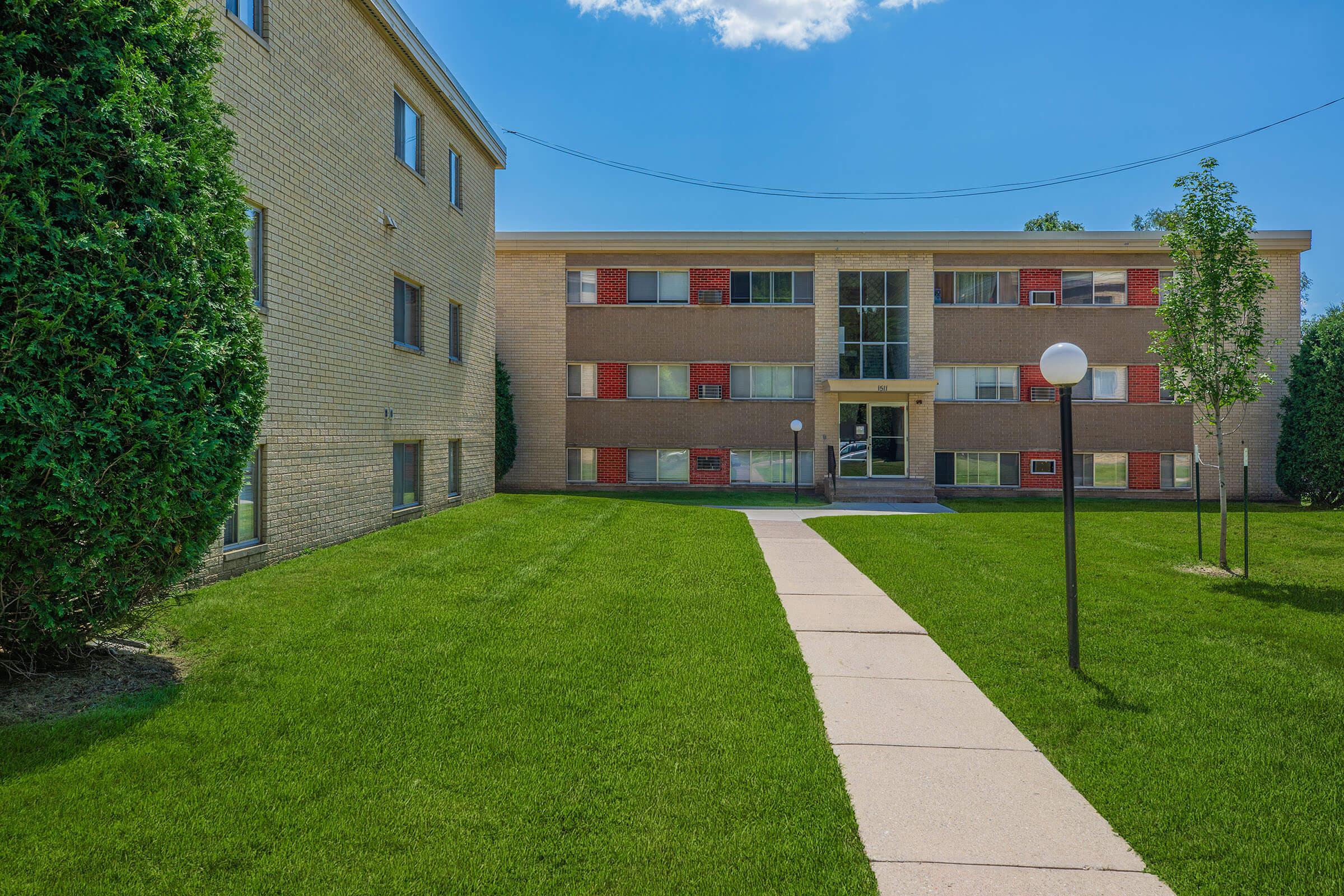 a large brick building with green grass