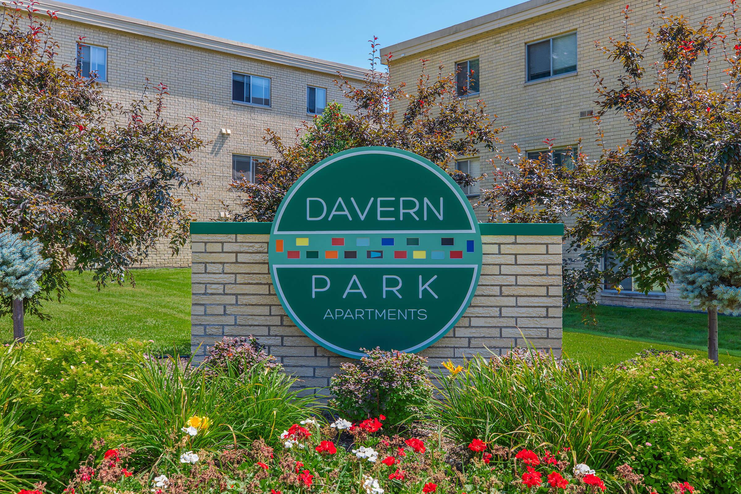 a sign above a flower garden in front of a building